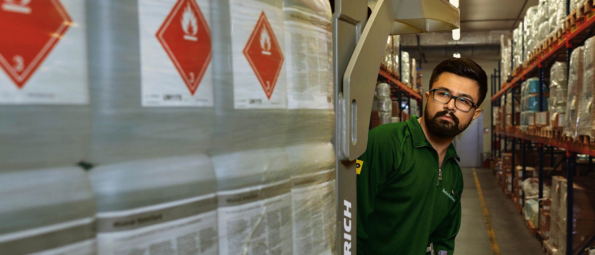 Ein Lagerarbeiter transportiert Gefahrgut auf einem Hubwagen im Gefahrstofflager.