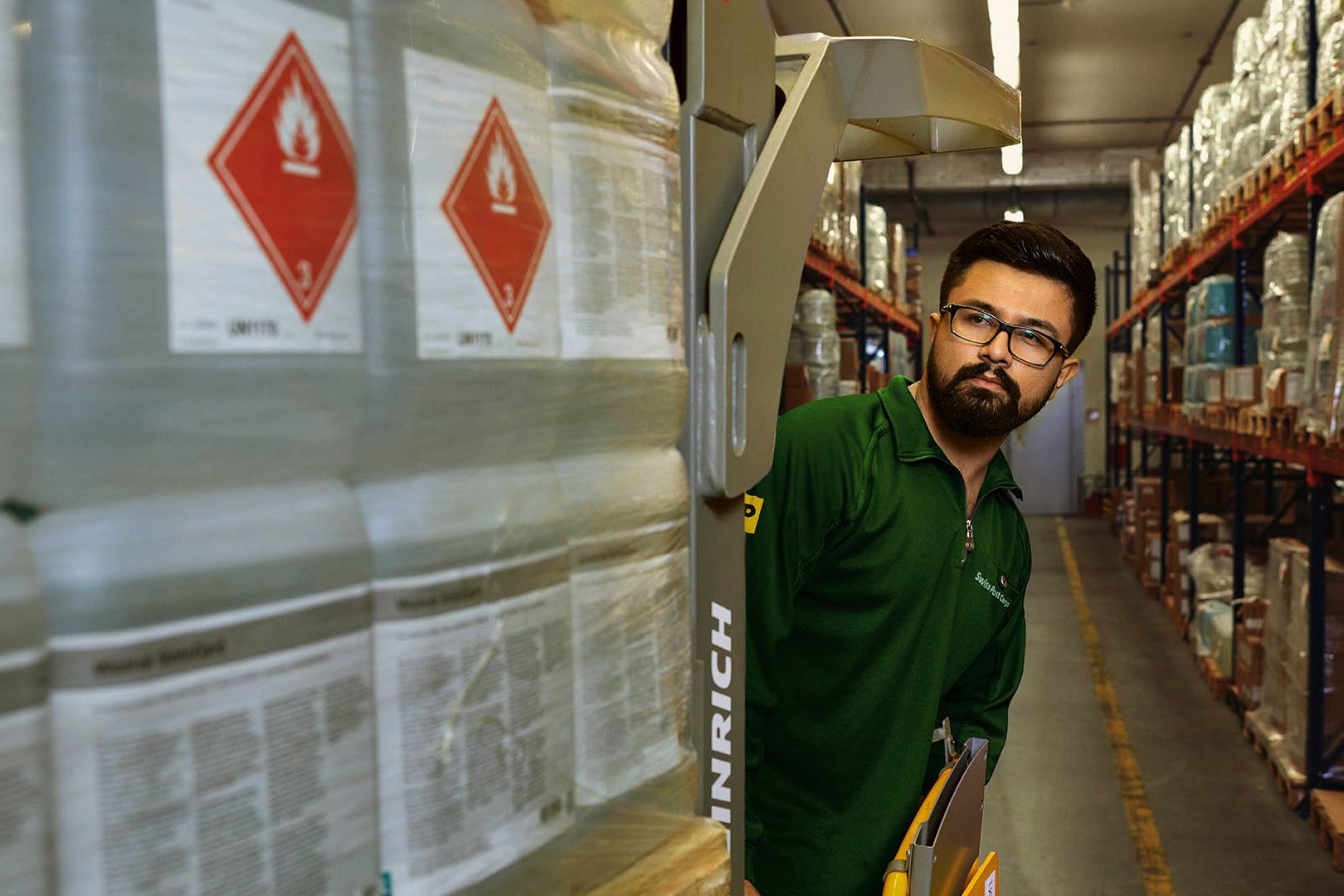 Un magasinier transporte des marchandises dangereuses sur un transpalette dans l’entrepôt de stockage des matières dangereuses.