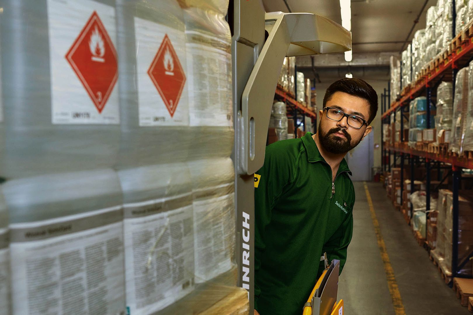 Ein Lagerarbeiter transportiert Gefahrgut mit einem Palettenhubwagen im Gefahrstofflager.