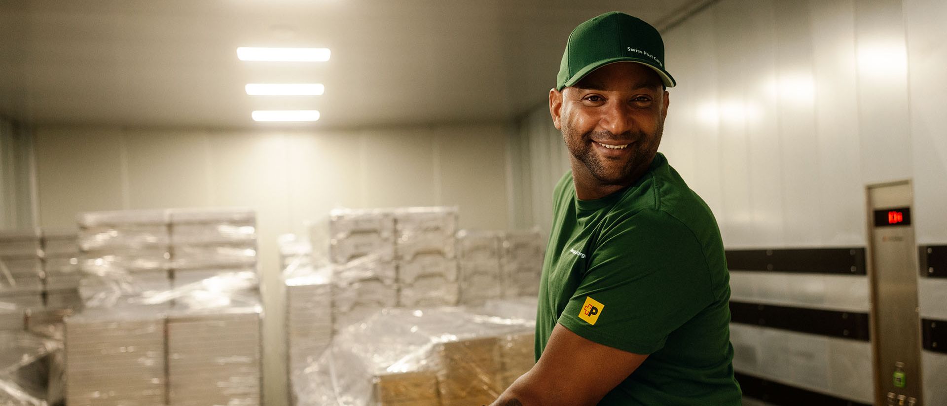 Ein Lagerarbeiter von Swiss Post Cargo fährt Stückgut auf einem Hubwagen in einen Fahrstuhl.