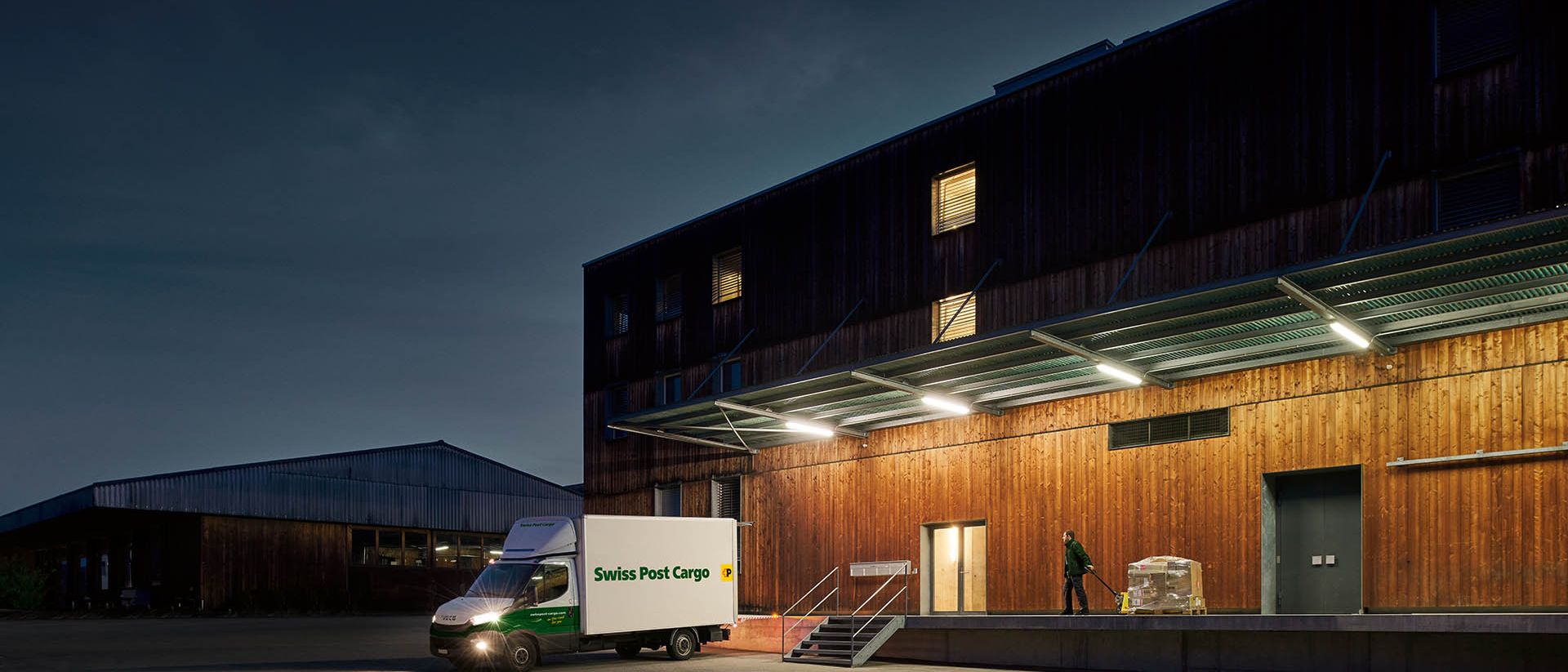 Ein Nachtkurier von Swiss Post Cargo liefert vor Tagesanbruch Waren an ein Lagergebäude.
