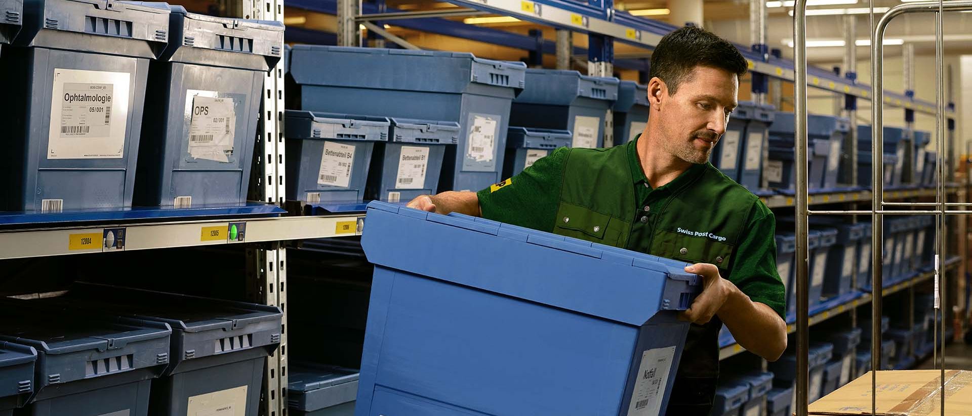 Un magazziniere carica una scatola con merci farmaceutiche da uno scaffale su un carrello.