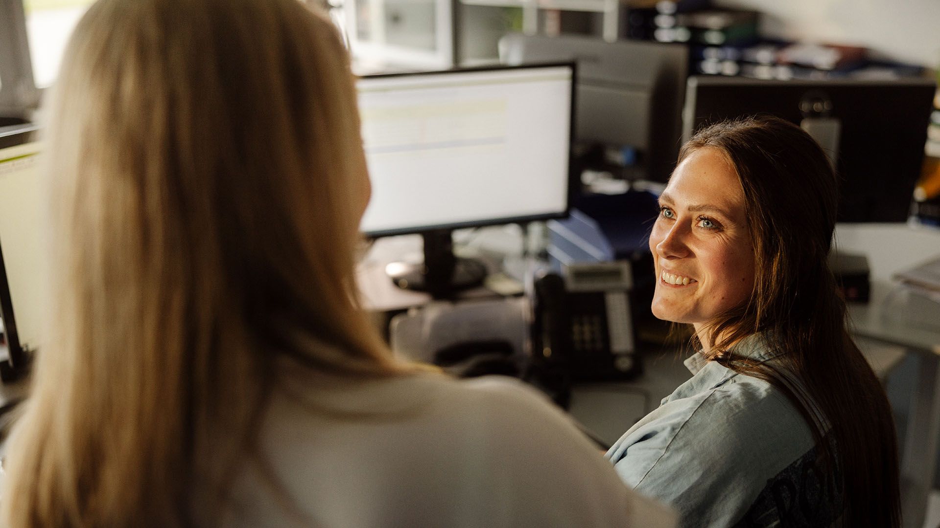 Swiss Post Cargo employees in conversation in front of the computer.
