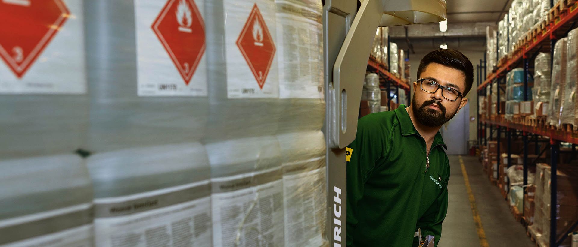 A warehouse worker transports hazardous goods on a pallet jack in the hazardous materials warehouse.