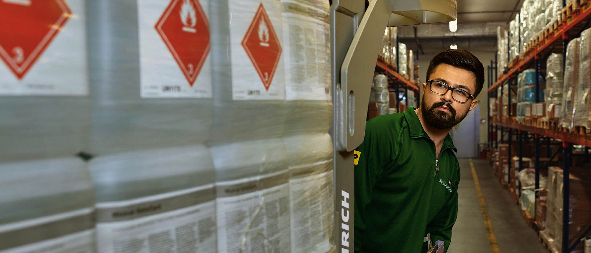 A warehouse worker transports hazardous goods on a pallet jack in the hazardous materials warehouse.