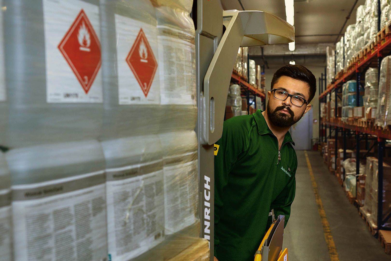 A warehouse worker transports hazardous goods on a pallet jack in the hazardous materials warehouse.