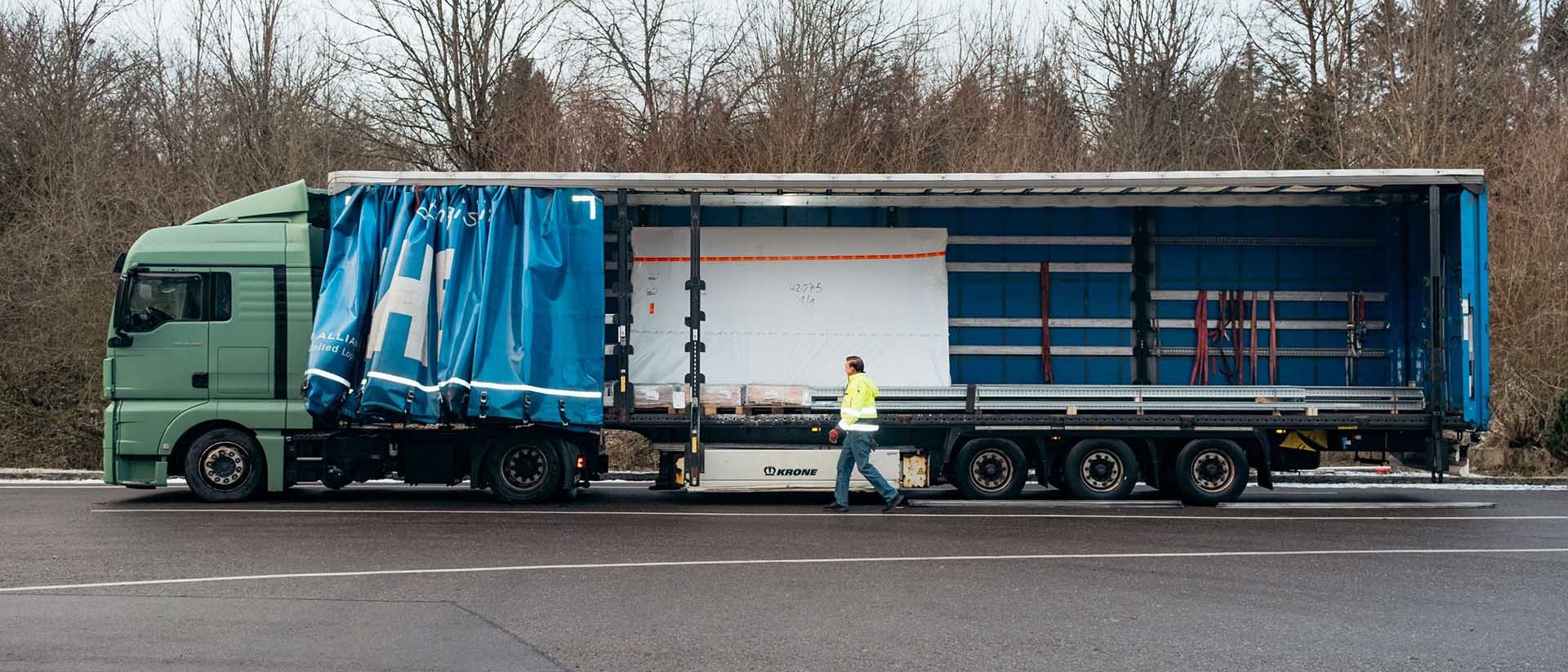 Francisc Szobo stands at the side in front of a lorry trailer with an open flat.