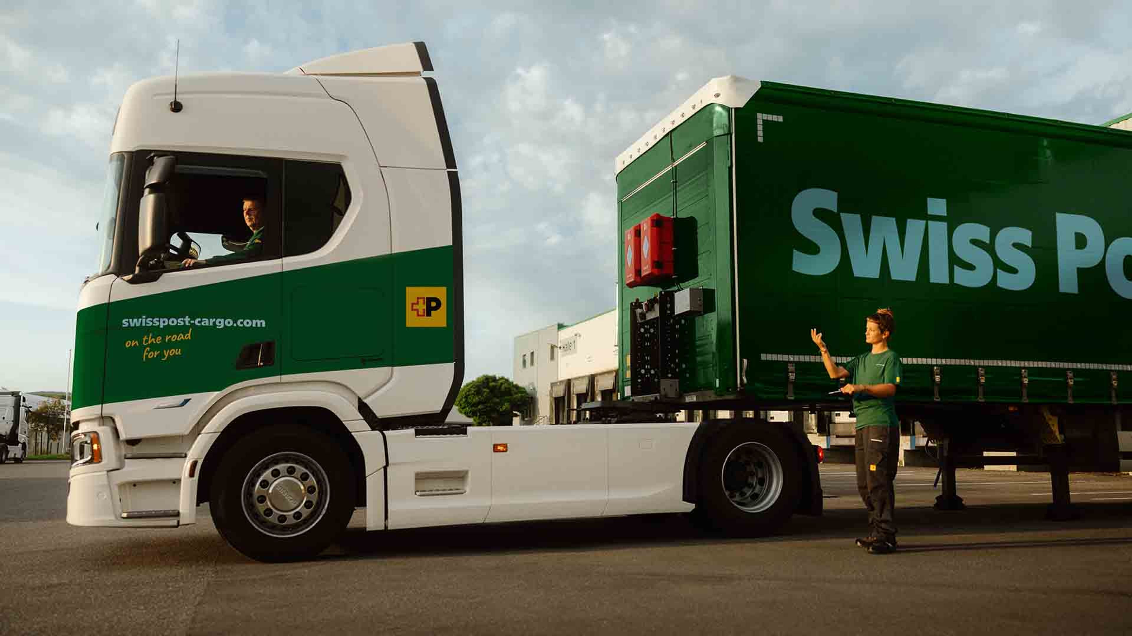 Un chauffeur de camion Swiss Post Cargo attelle une remorque, assisté par une collègue.