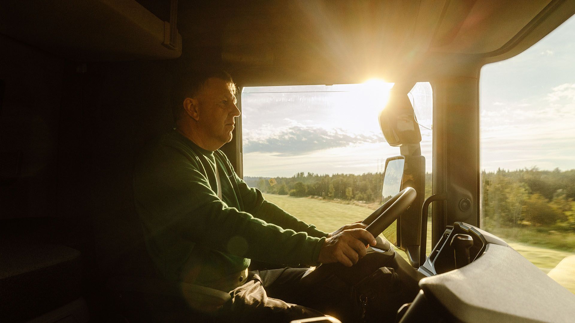 Un chauffeur de camion de Swiss Post Cargo conduit son véhicule en trajet direct à travers un paysage ensoleillé.