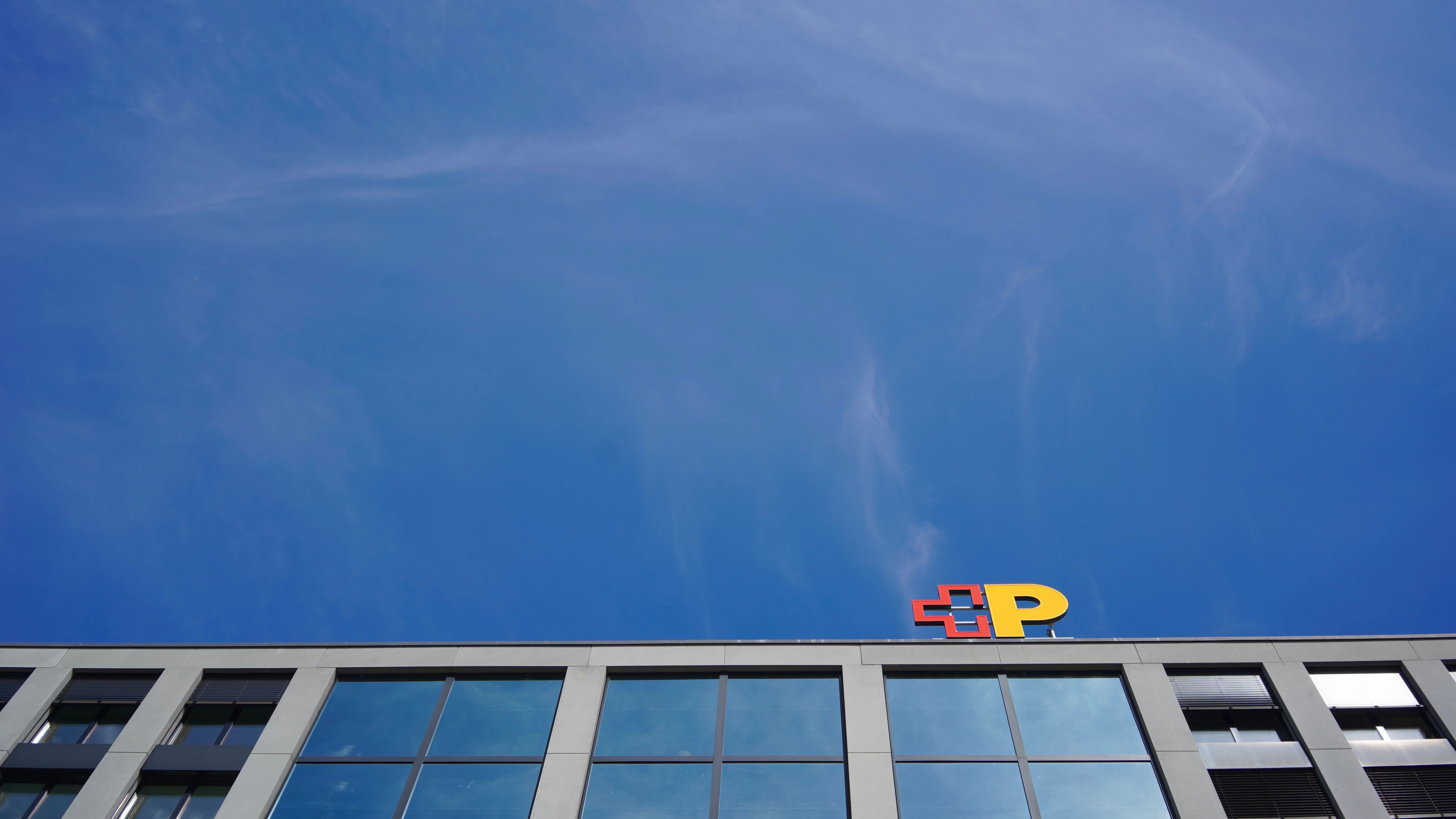 Gebäude mit Logo der Schweizerischen Post vor blauem Himmel
