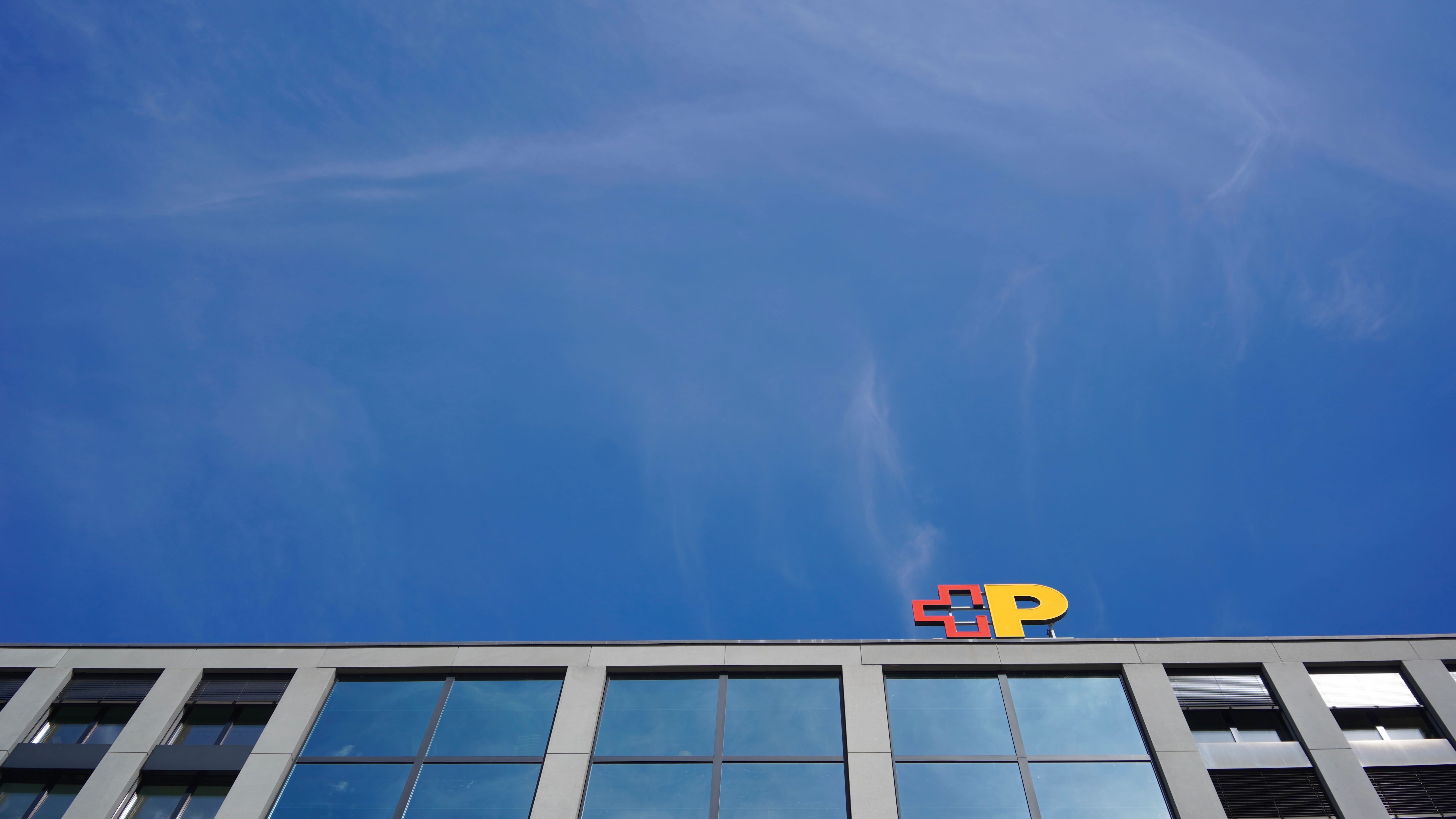 Gebäude mit Logo der Schweizerischen Post vor blauem Himmel