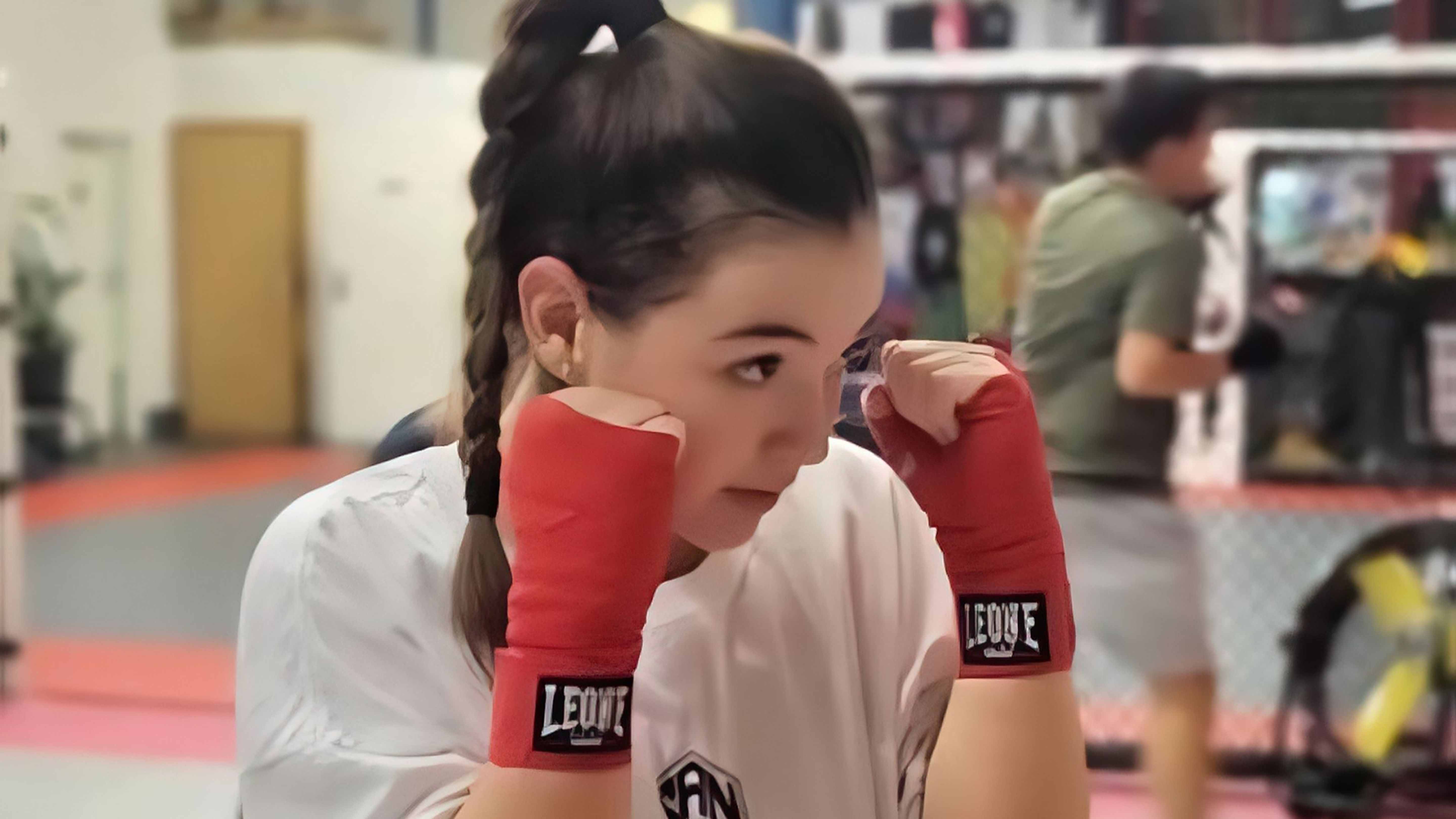 Donna durante un allenamento di boxe con le fasce rosse in un palazzetto dello sport.