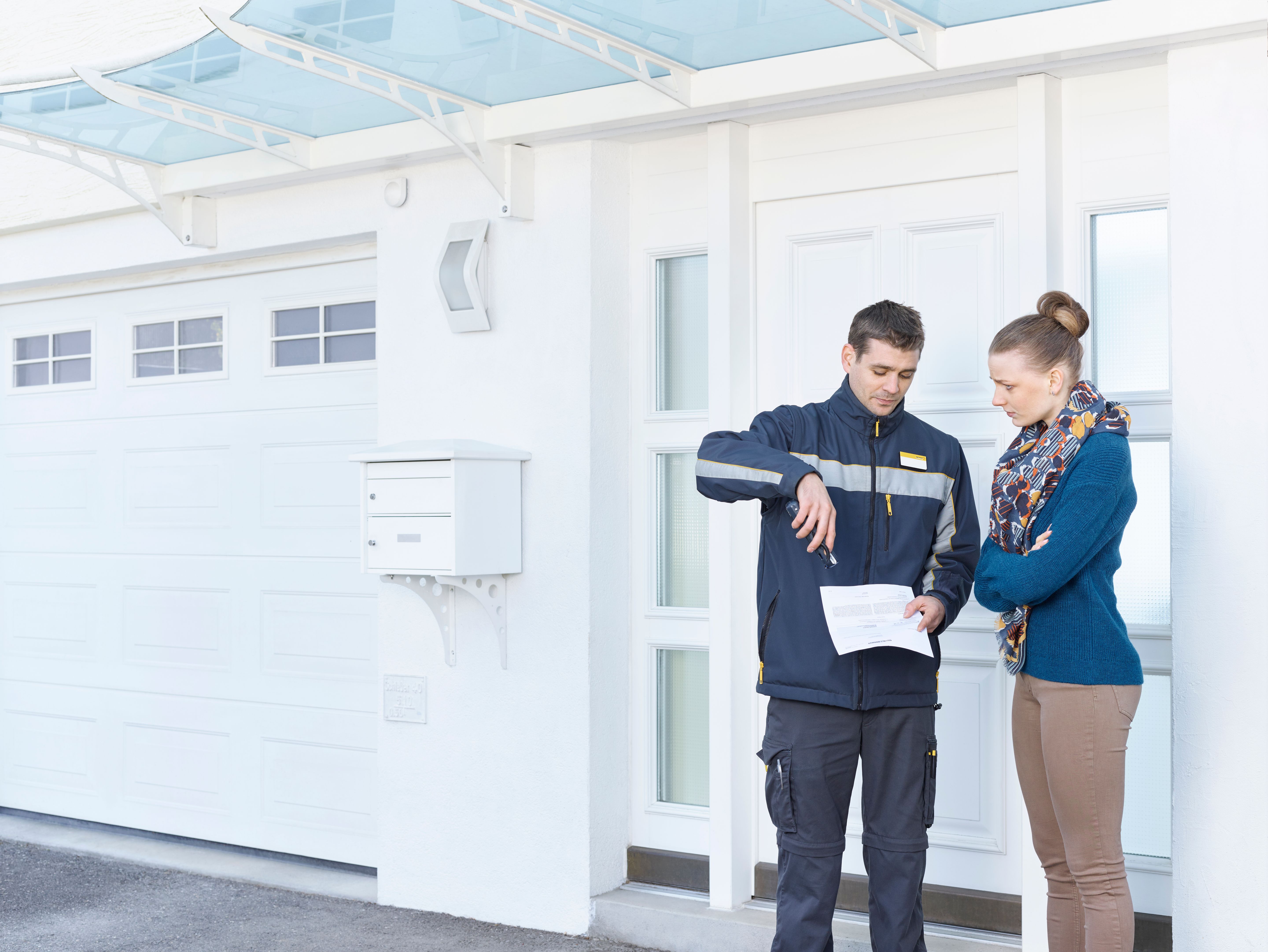 Postmitarbeiter erklärt einer Frau vor Haustür ein Dokument