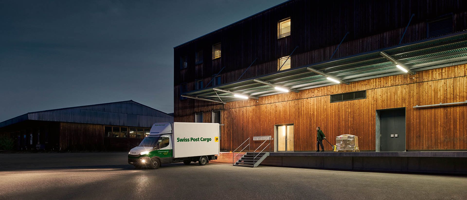 Ein Nachtkurier von Swiss Post Cargo liefert vor Tagesanbruch Waren an ein Lagergebäude.