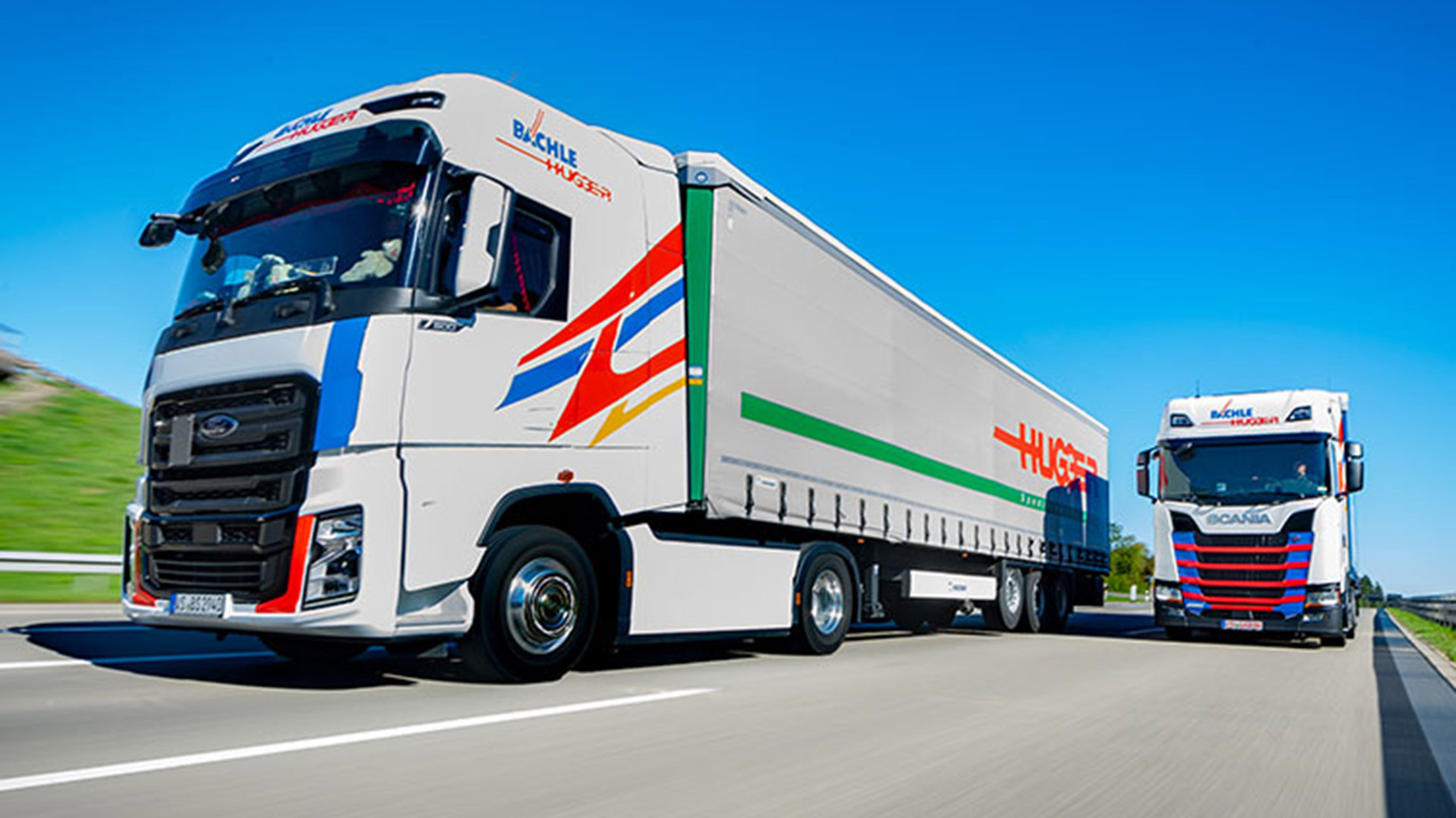 Ein Swiss Post Cargo LKW und ein Bächle LKW stehen nebeneinander.