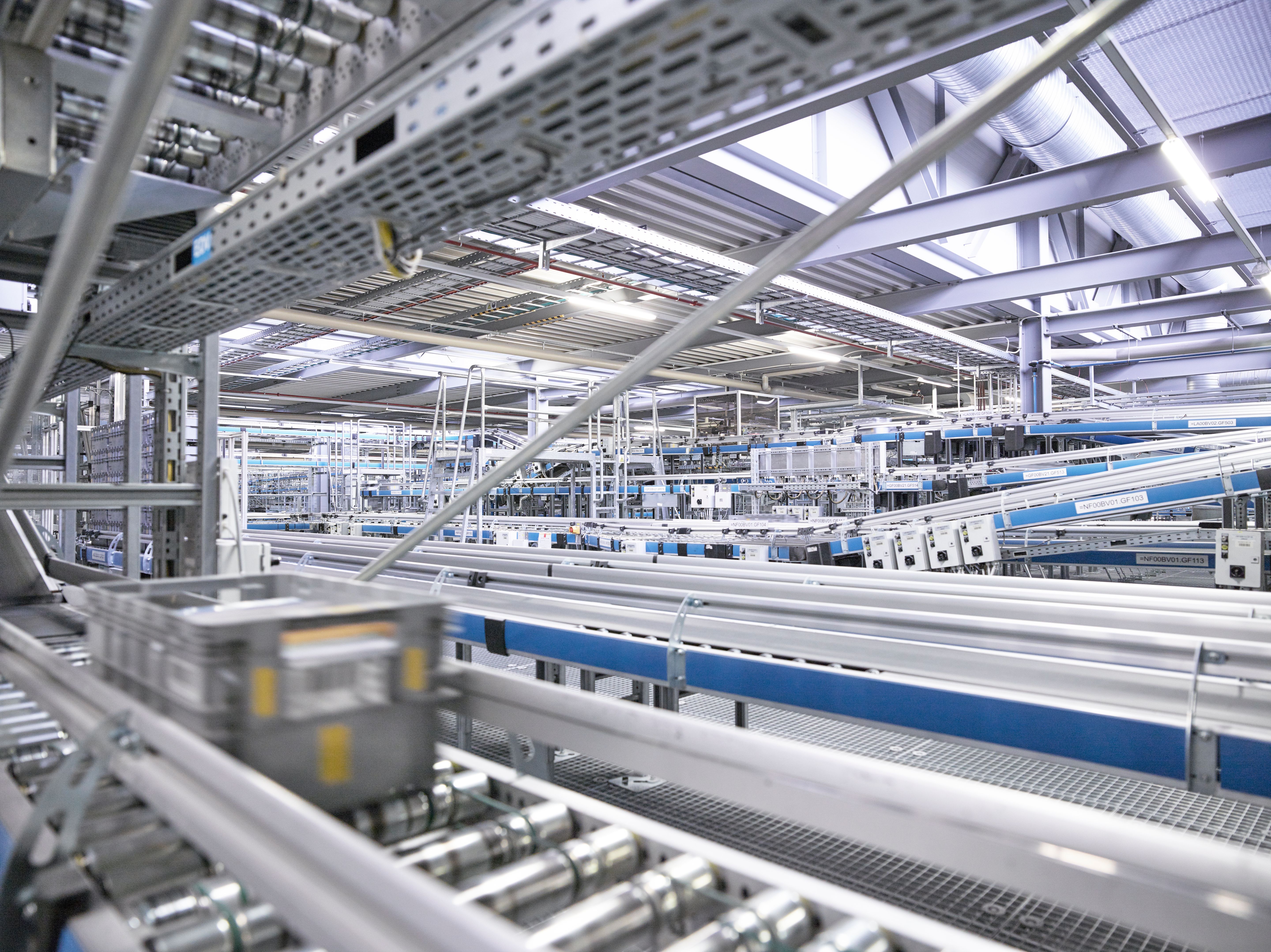 Automatisiertes Fördersystem in einer Logistikanlage mit Transportbehältern auf Rollenbahnen