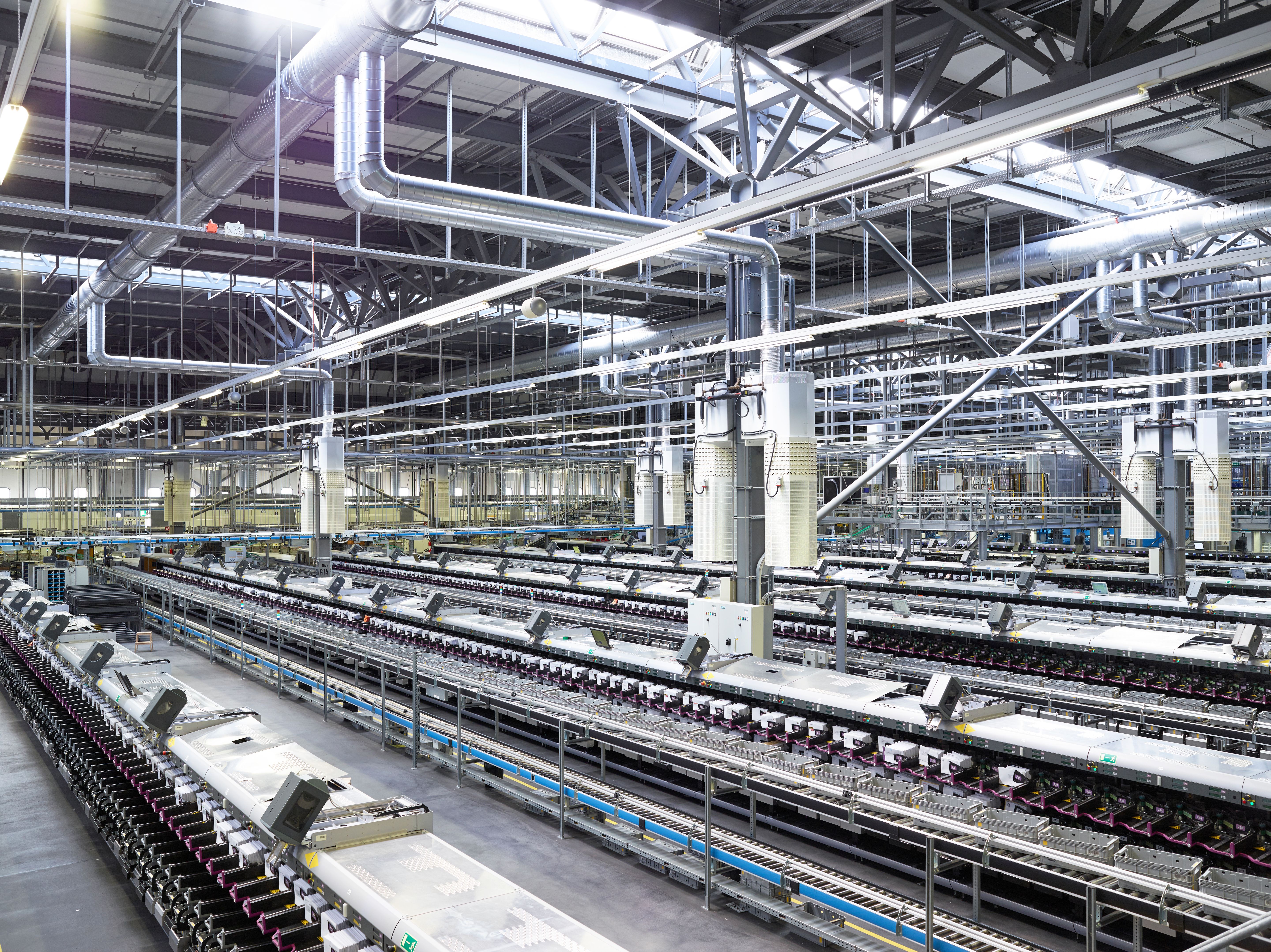 Blick in eine grosse, moderne Industriehalle mit komplexen Maschinen und Rohrleitungen an der Decke