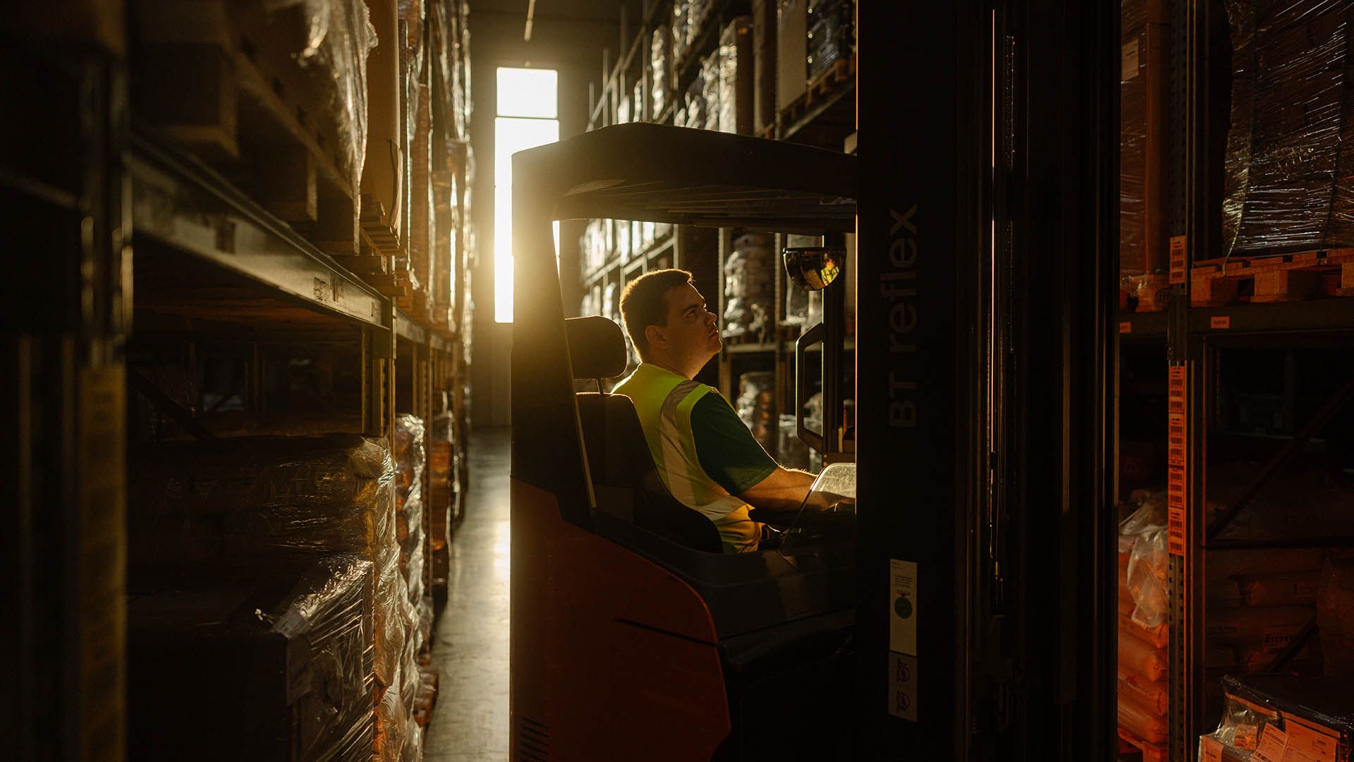 In a warehouse, a Swiss Post Cargo employee drives a forklift between shelves.