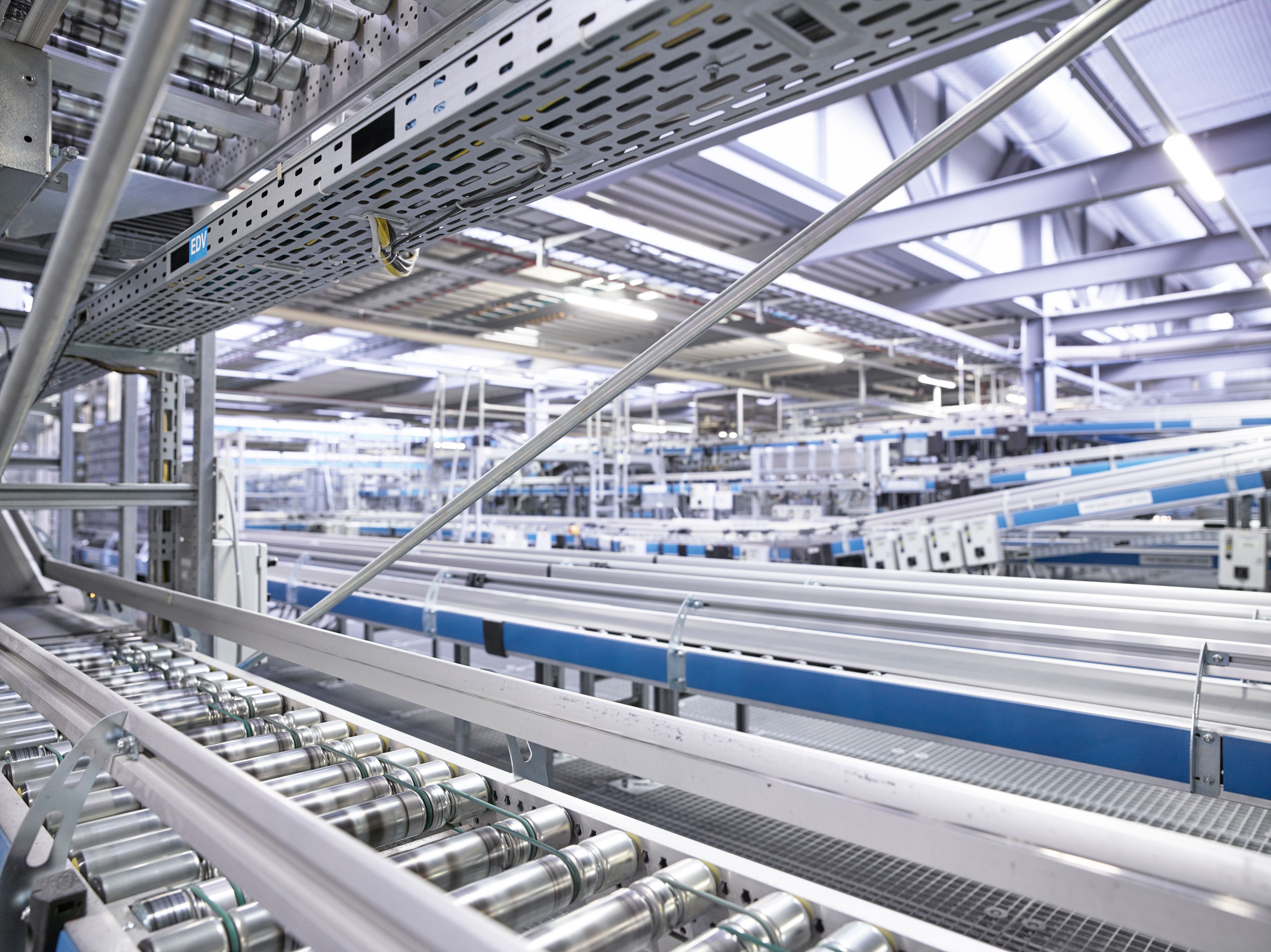 Innenansicht einer modernen Logistikanlage mit Förderbändern und Metallkonstruktionen.