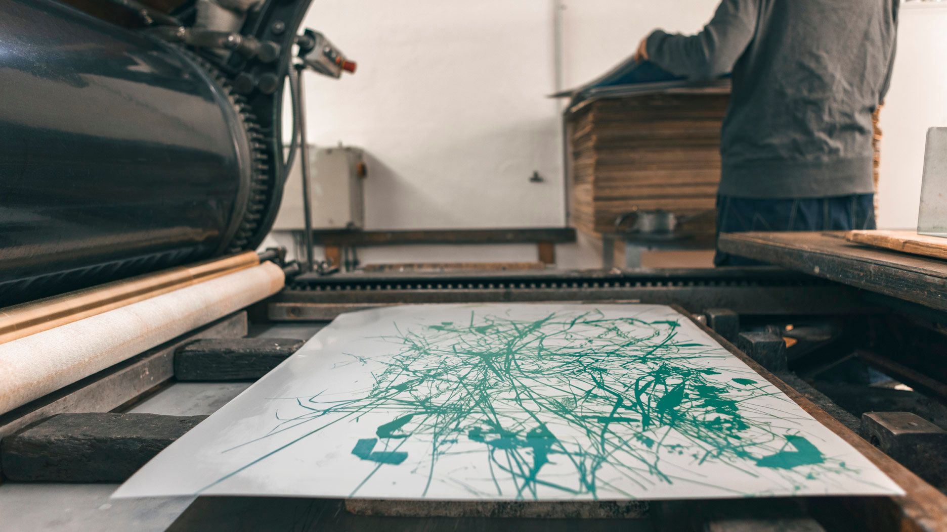 Ein Kunstwerk mit grünen Linien wird auf einer Druckmaschine in einem hellen Raum erstellt.