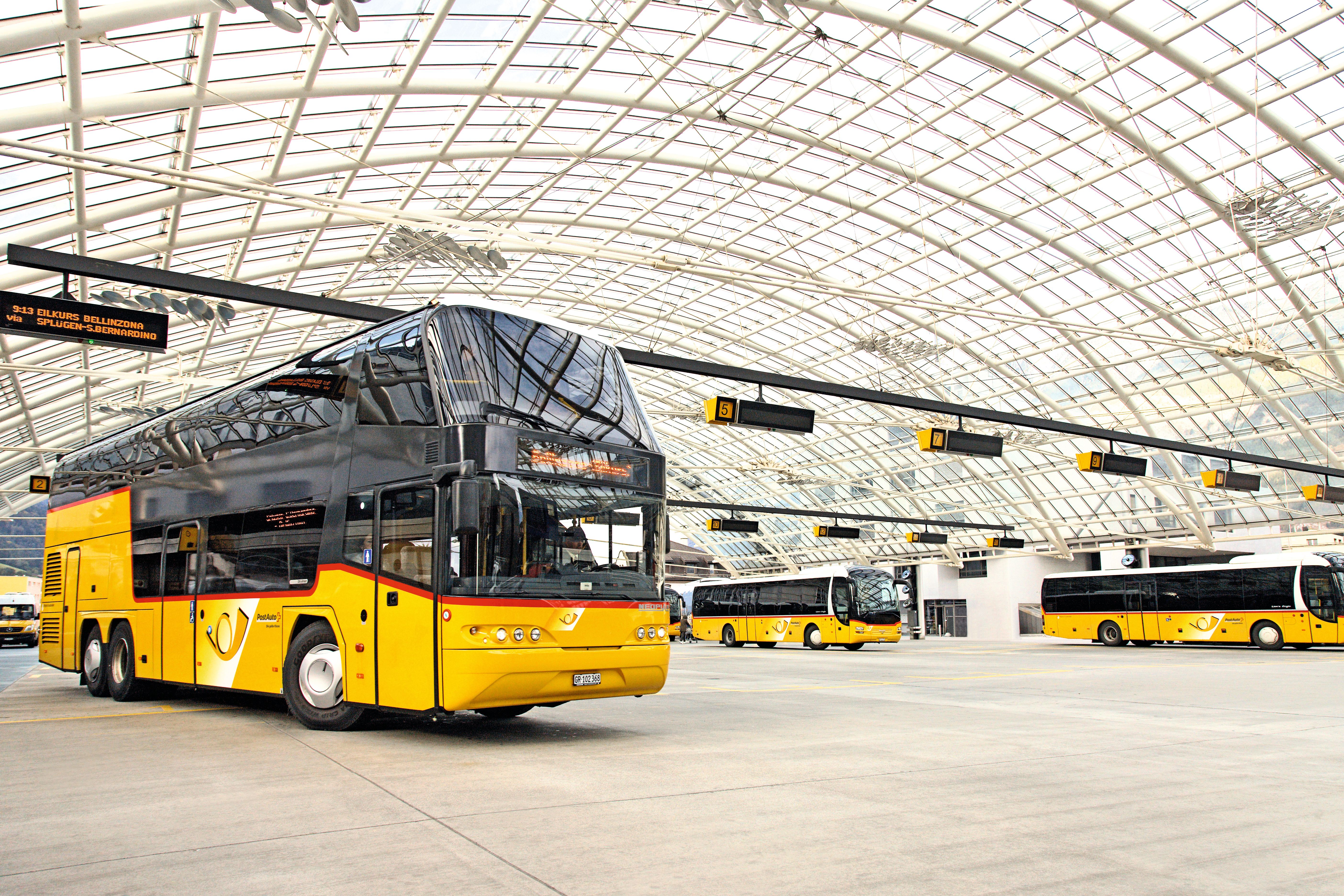 Gelb-schwarzer Doppeldeckerbus in überdachter Busstation mit Glasdach