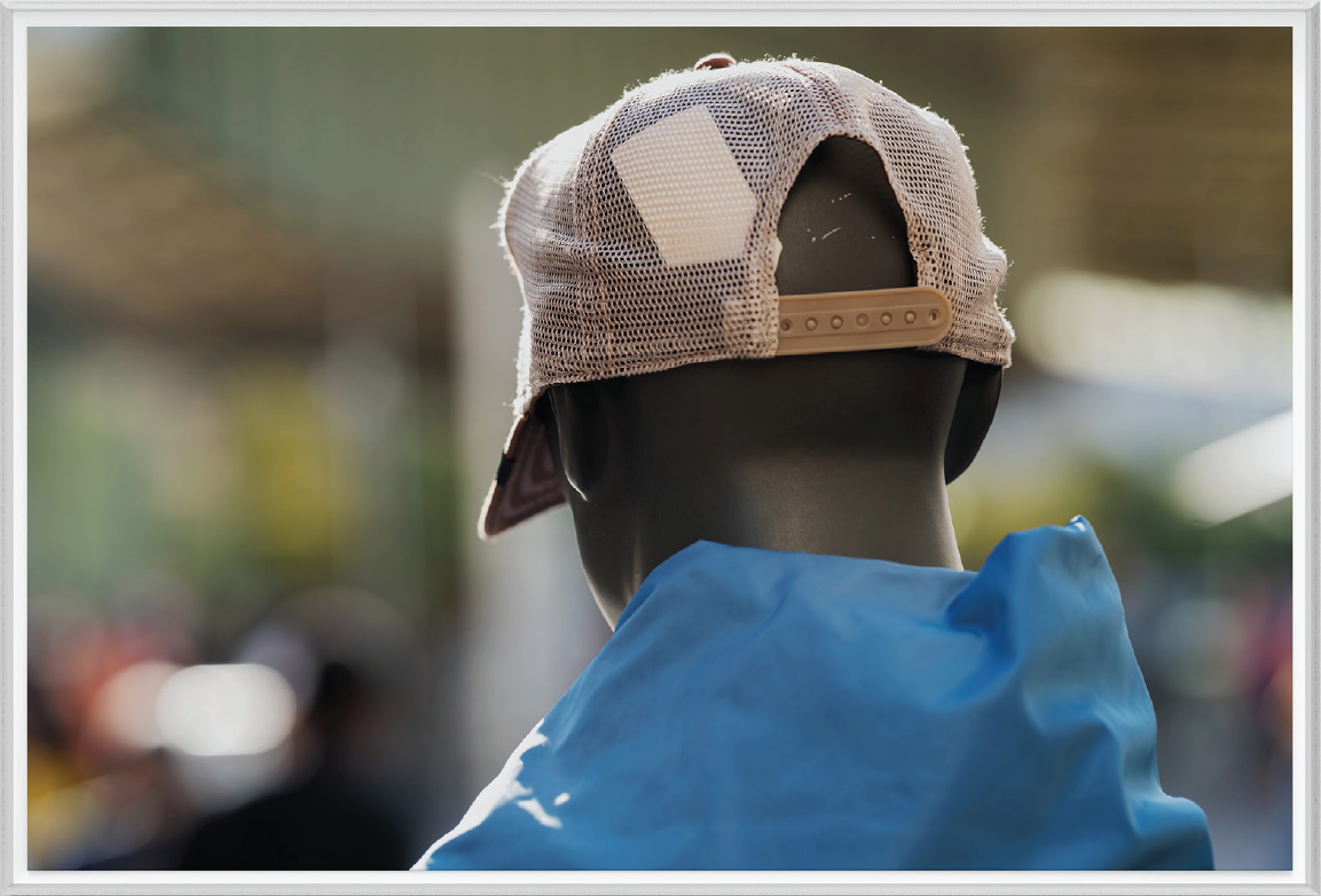 Person von hinten mit Netz-Cap und blauem Oberteil vor unscharfem Hintergrund.