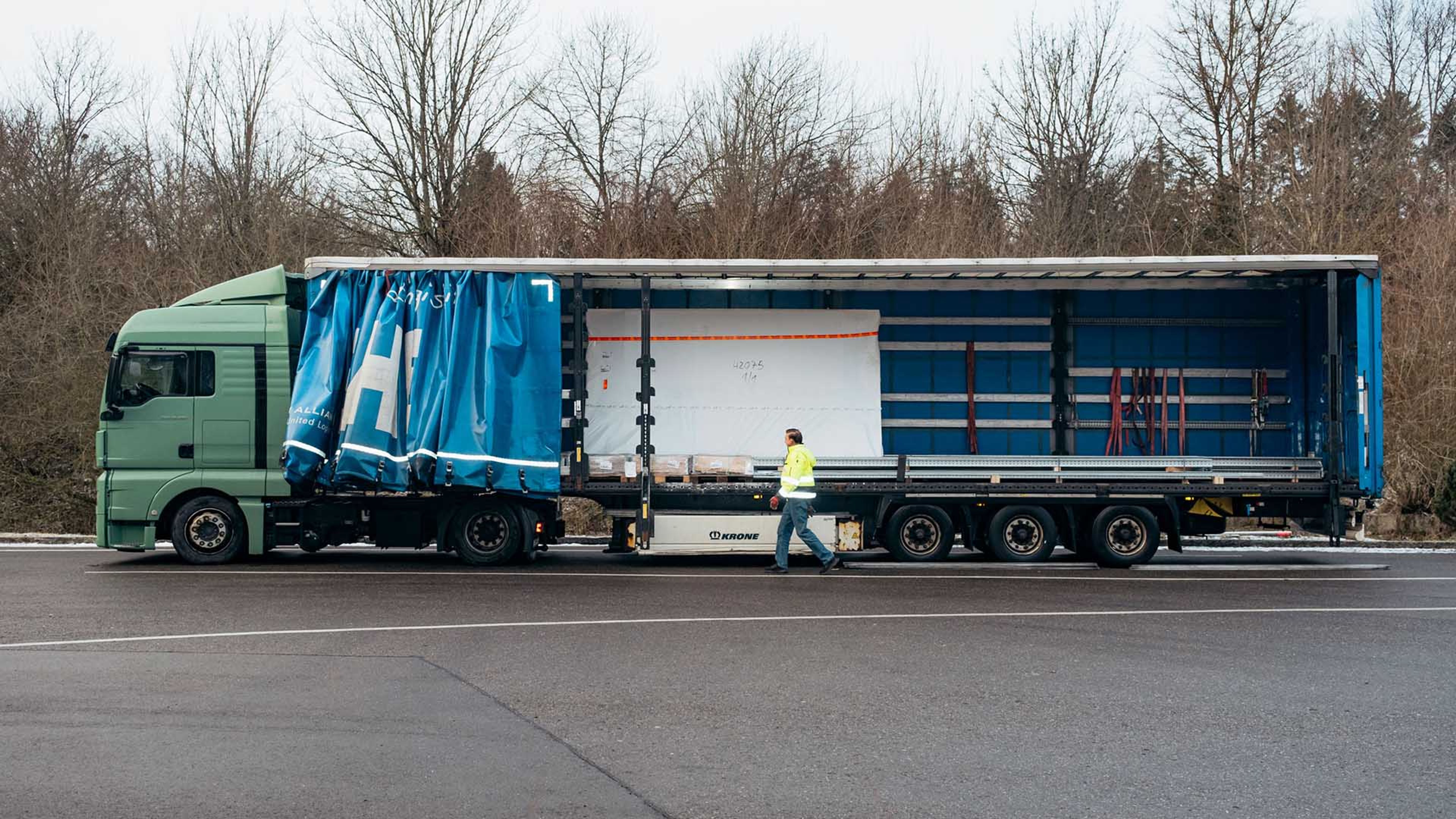 Francisc Szobo stands at the side in front of a lorry trailer with an open flat.