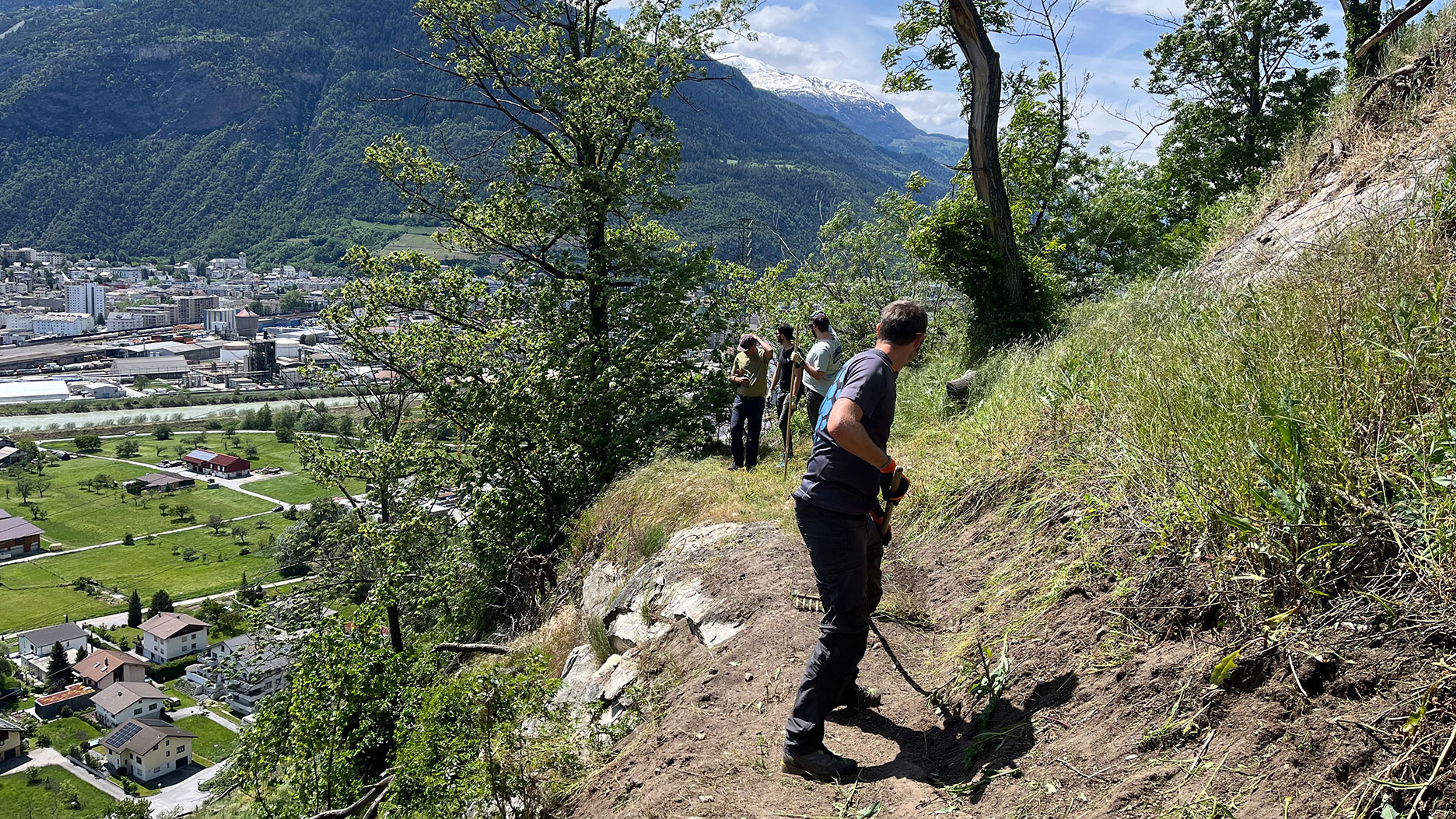 Più persone su un percorso pendente con città e montagne sullo sfondo.