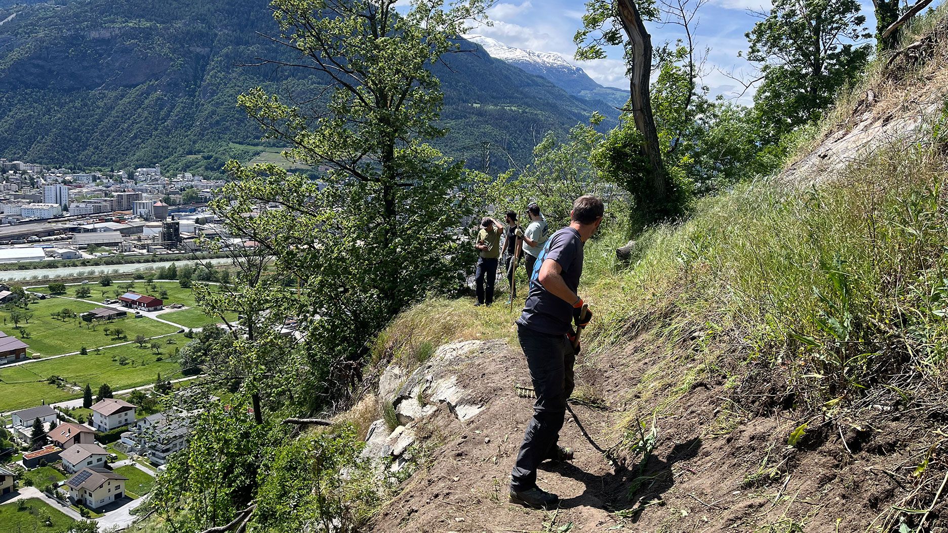 Più persone su un percorso pendente con città e montagne sullo sfondo.