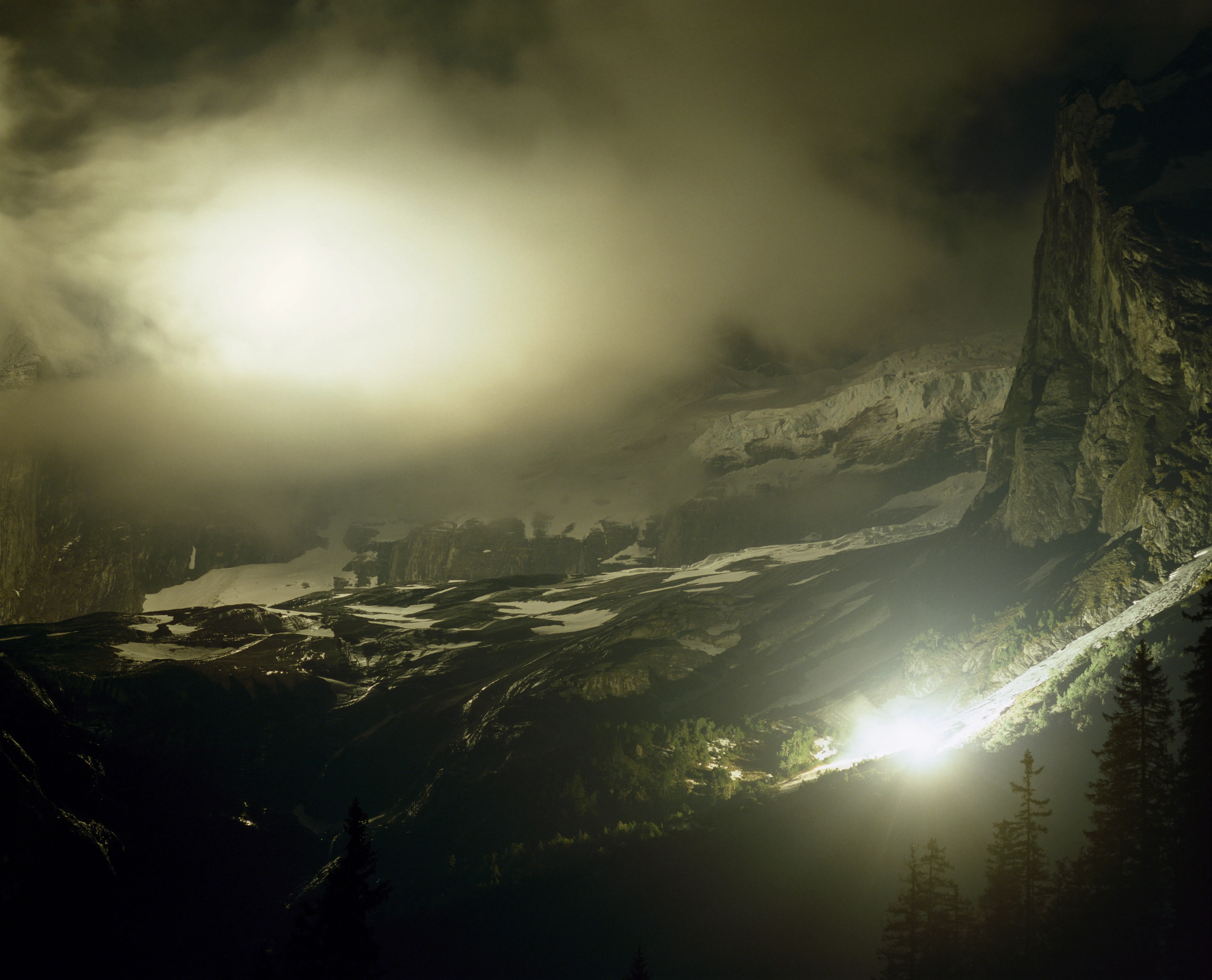 Foggy mountain peak at night with two bright lights.