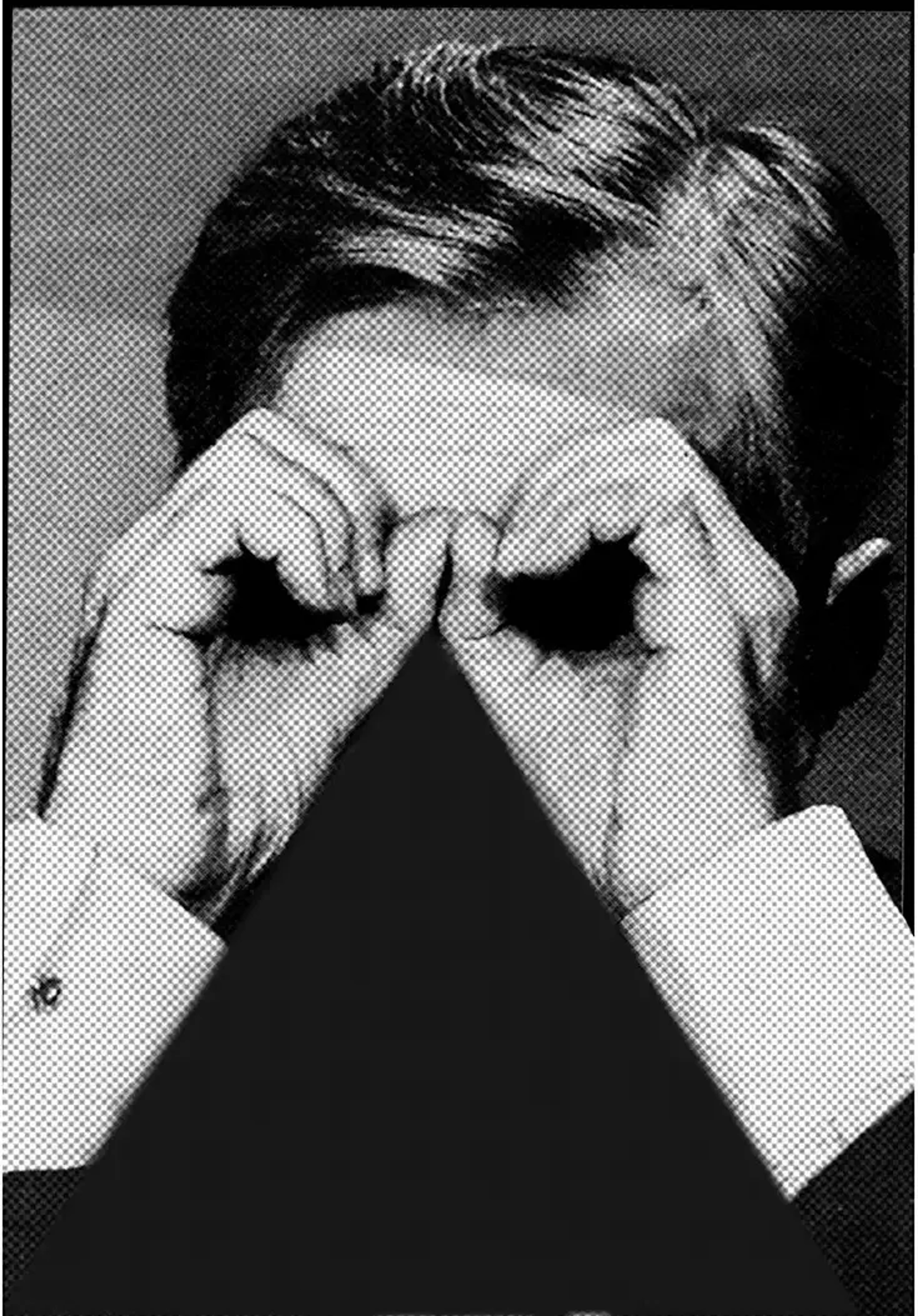 A person holds his hands in the shape of glasses in front of his face with a black triangle underneath.