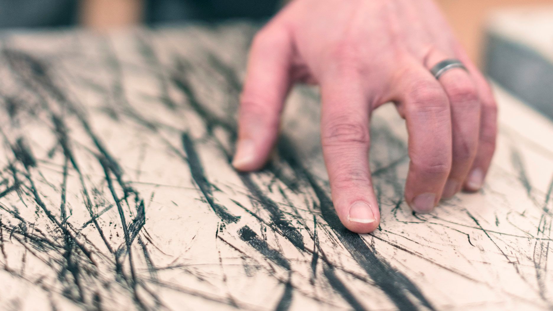Eine Hand berührt eine mit schwarzen Linien versehene Oberfläche.
