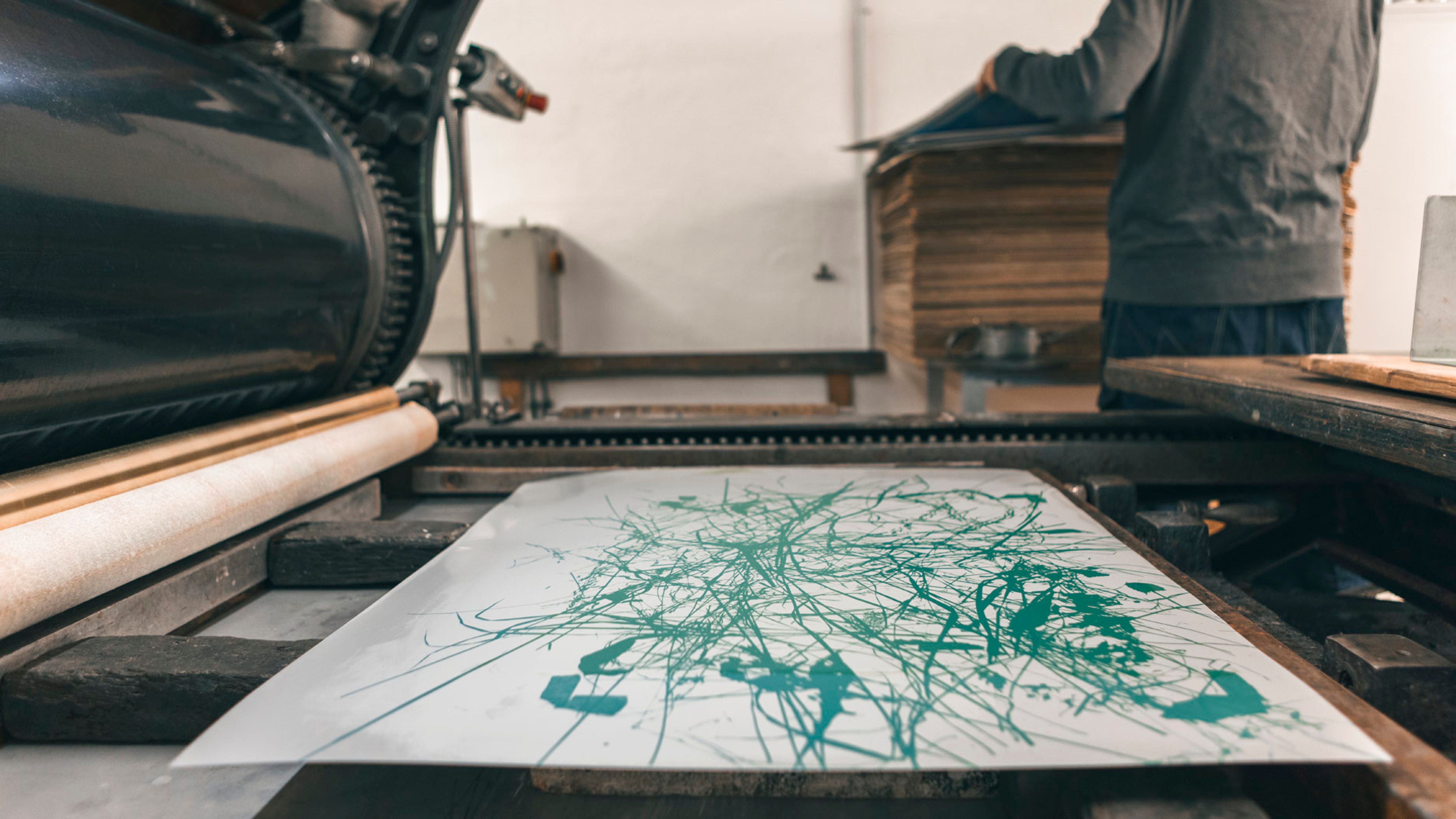 Ein Kunstwerk mit grünen Linien wird auf einer Druckmaschine in einem hellen Raum erstellt.