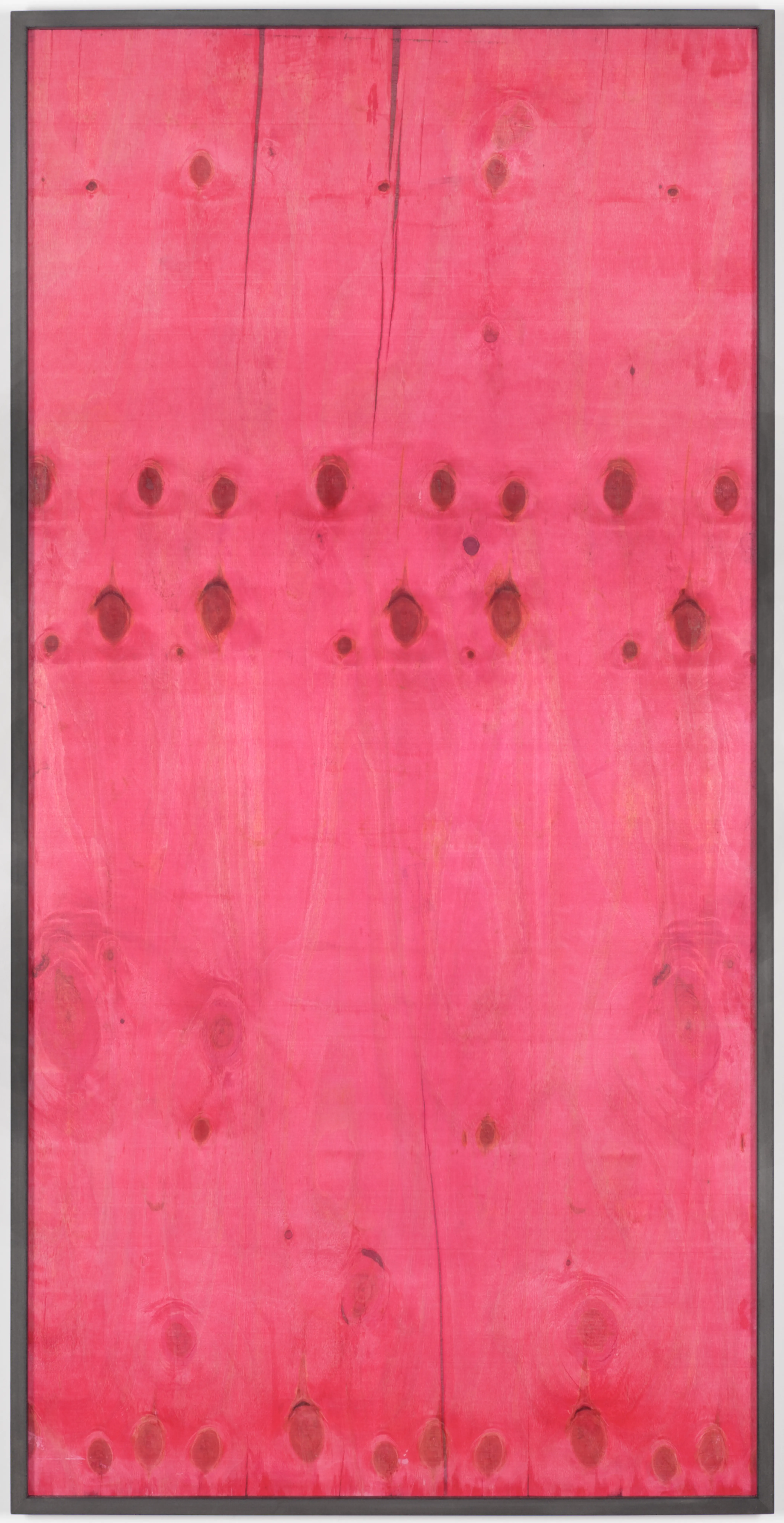 Wooden surface in bright pink with visible grain and knot holes in a narrow frame.