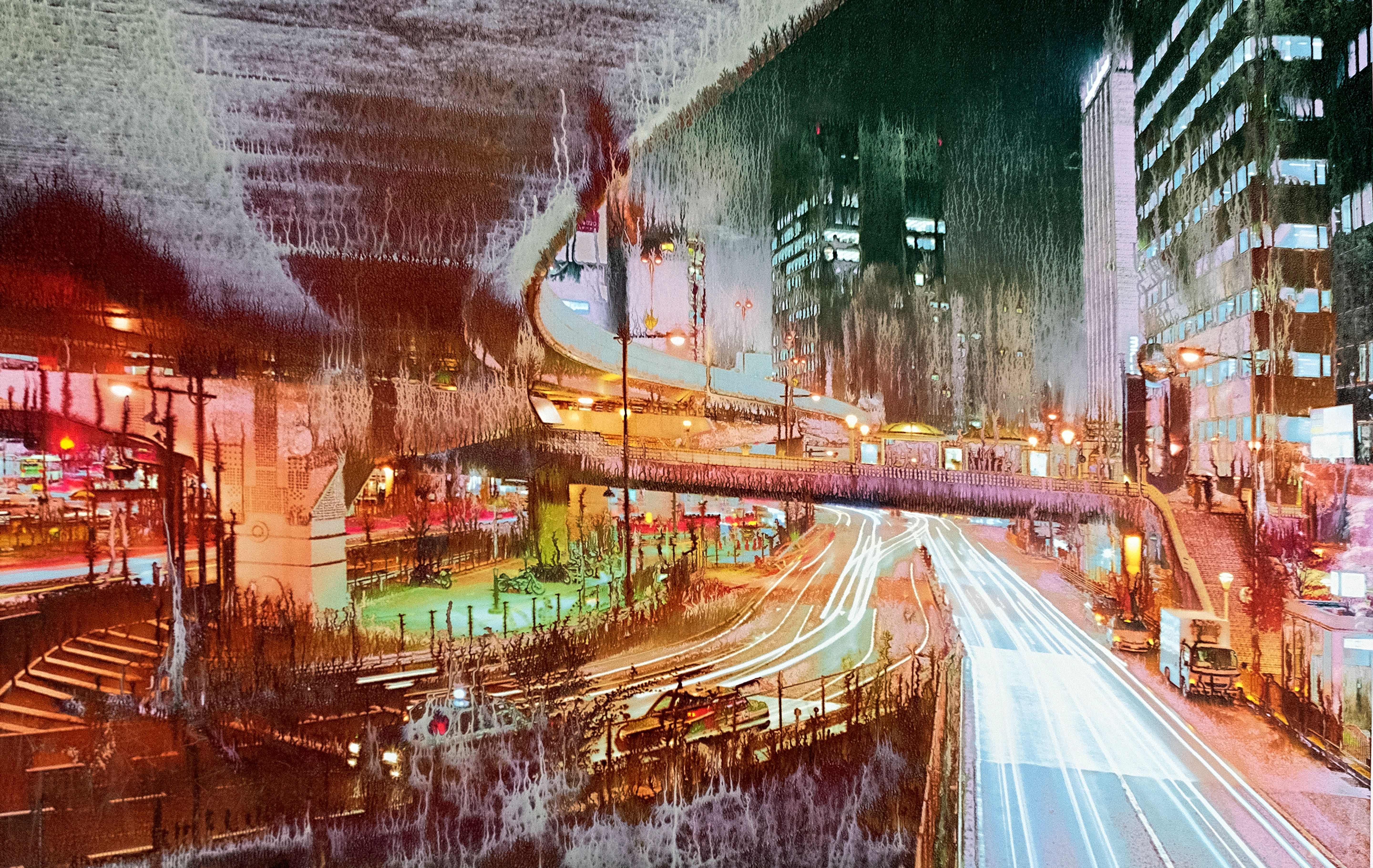 Night view of a city with traces of light from vehicles and urban architecture.
