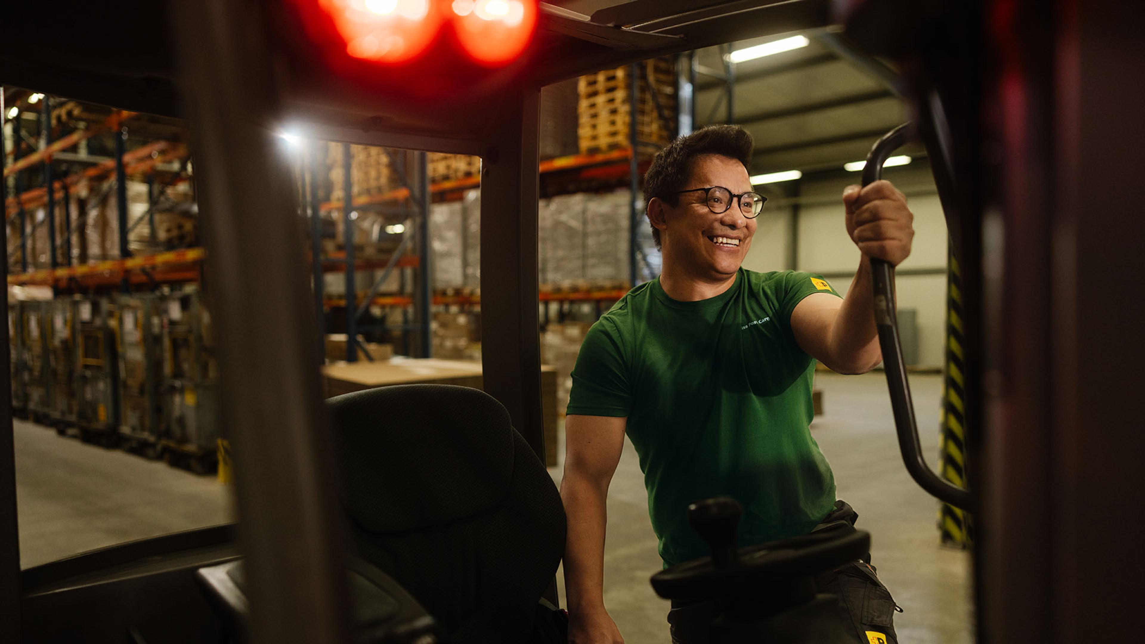 In a warehouse, a Swiss Post Cargo employee gets into the cabin of a forklift.