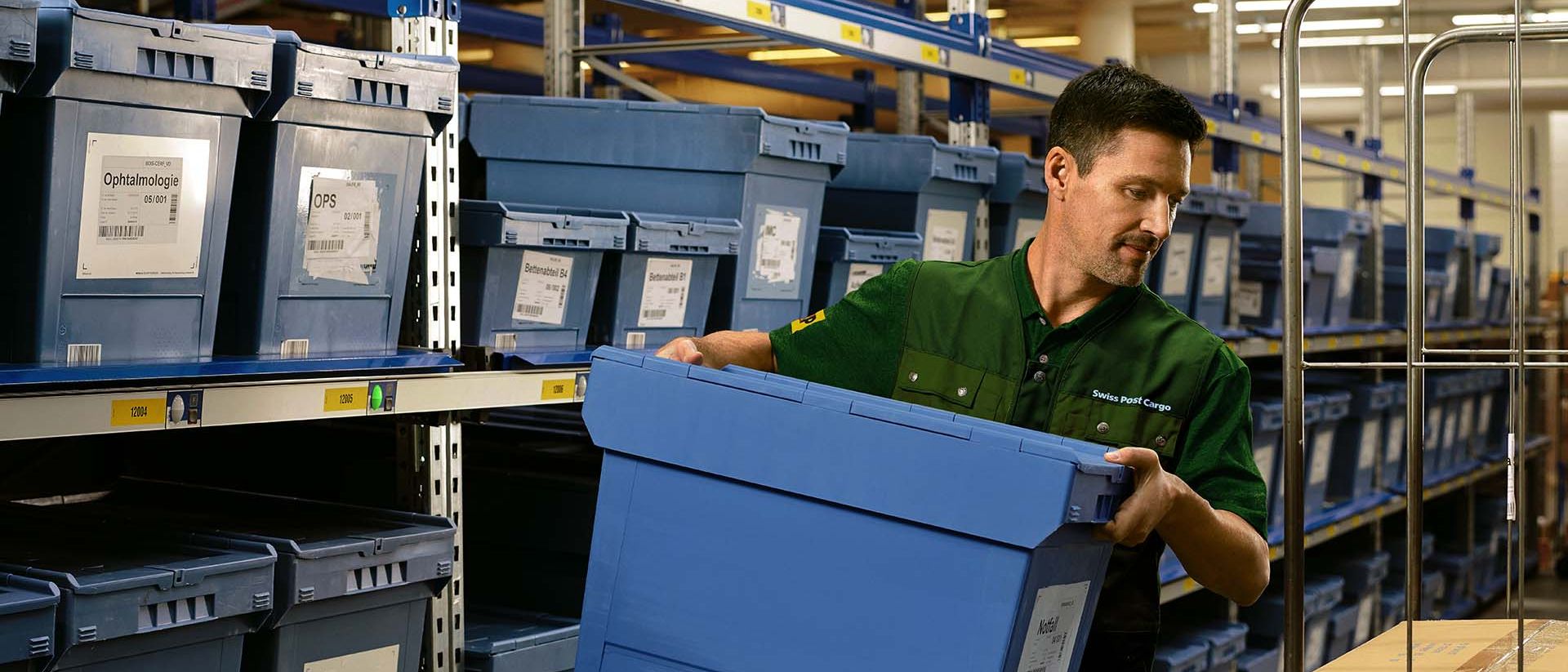 Un magazziniere carica una scatola con merci farmaceutiche da uno scaffale su un carrello.