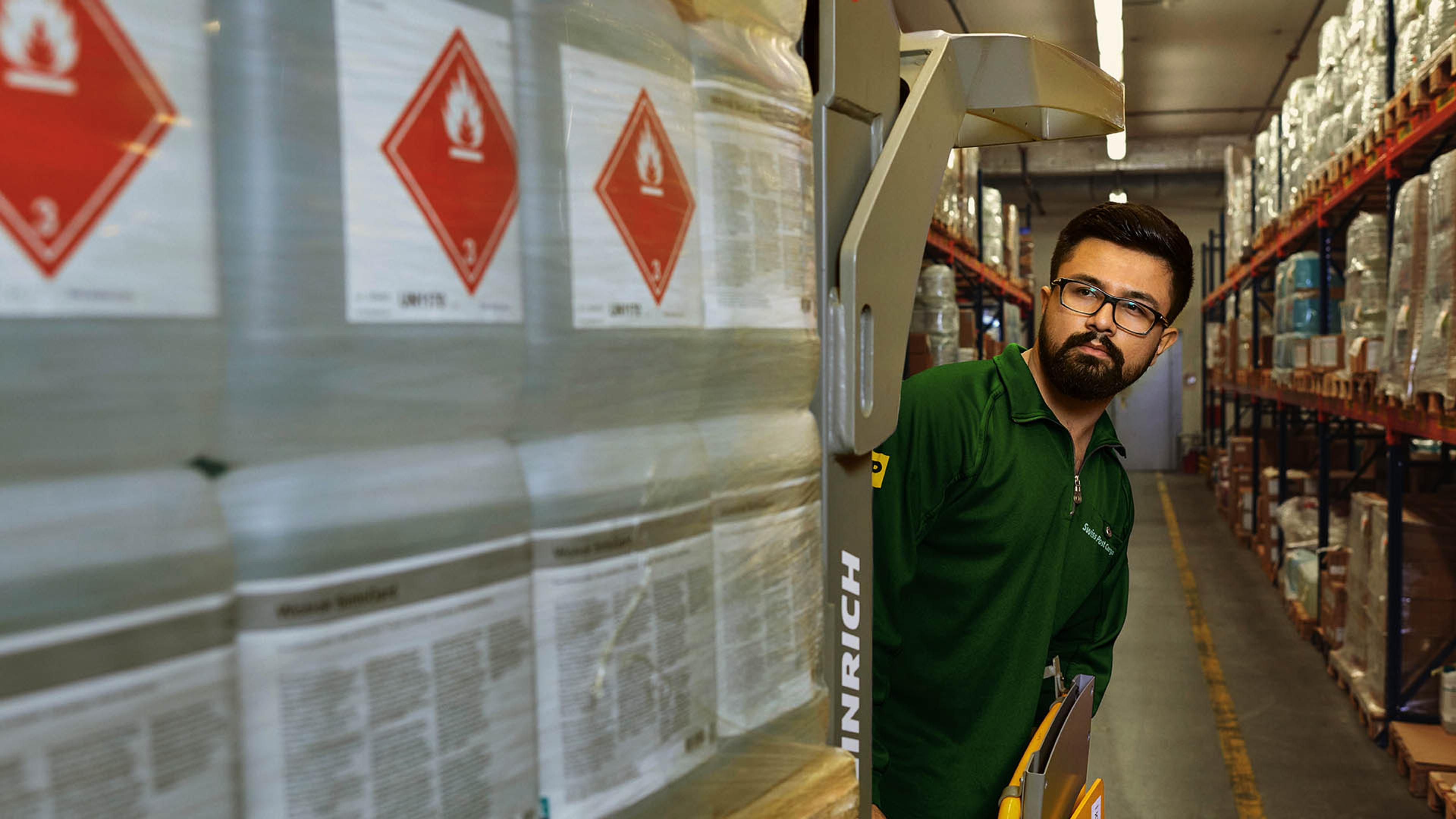 A warehouse worker transports hazardous goods on a pallet jack in the hazardous materials warehouse.