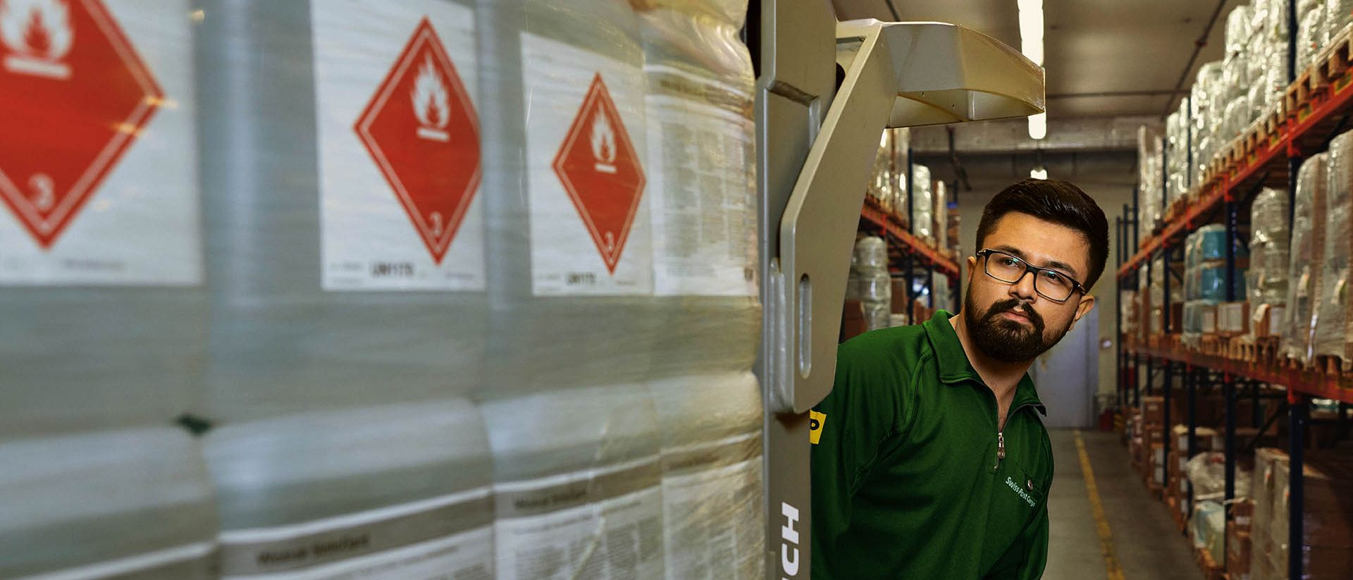 Un magasinier transporte des marchandises dangereuses sur un transpalette dans l’entrepôt de stockage des matières dangereuses.