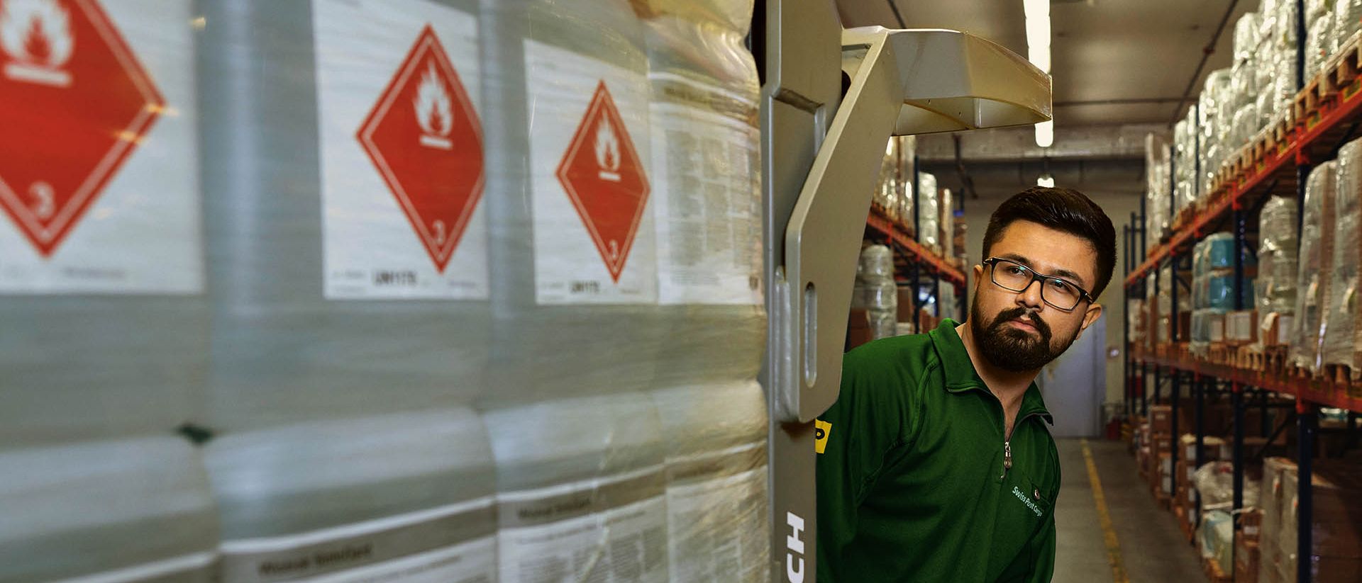 Ein Lagerarbeiter transportiert Gefahrgut auf einem Hubwagen im Gefahrstoff-Lager.