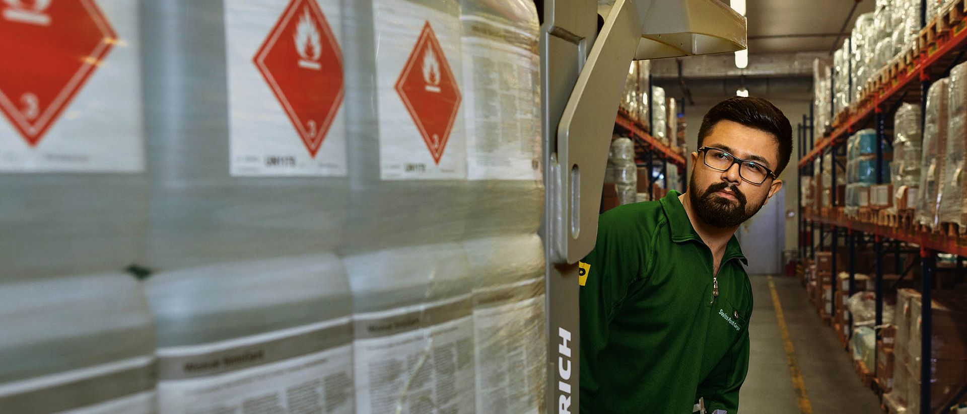 Un magasinier transporte des marchandises dangereuses sur un transpalette dans l’entrepôt de stockage des matières dangereuses.