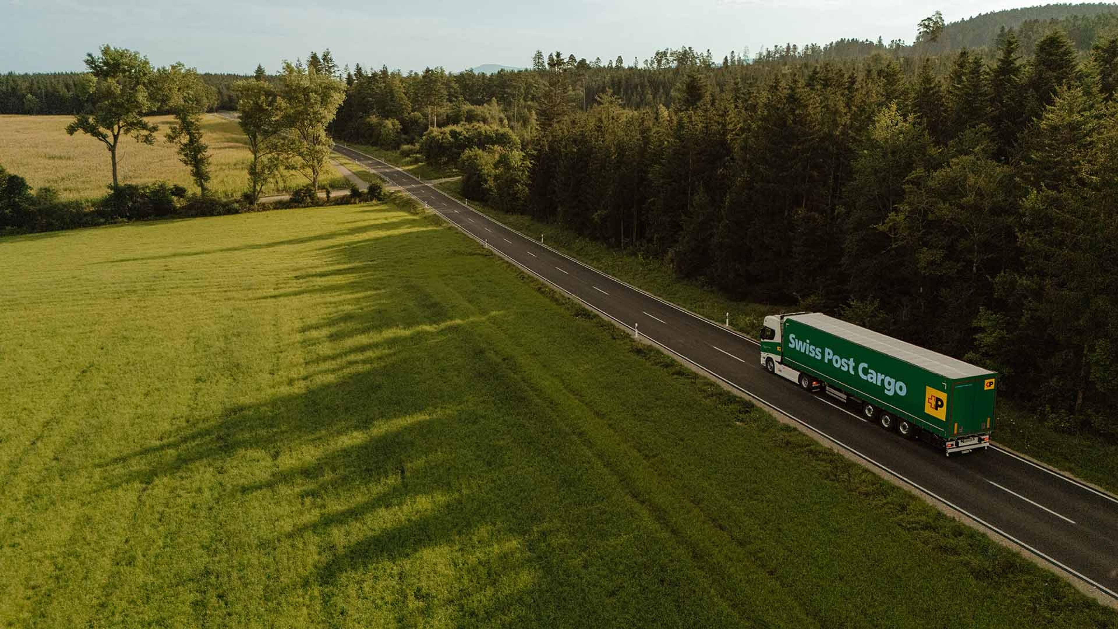 Swiss Post Cargo Lastwagen fährt am Waldrand entlang auf einer Landstrasse