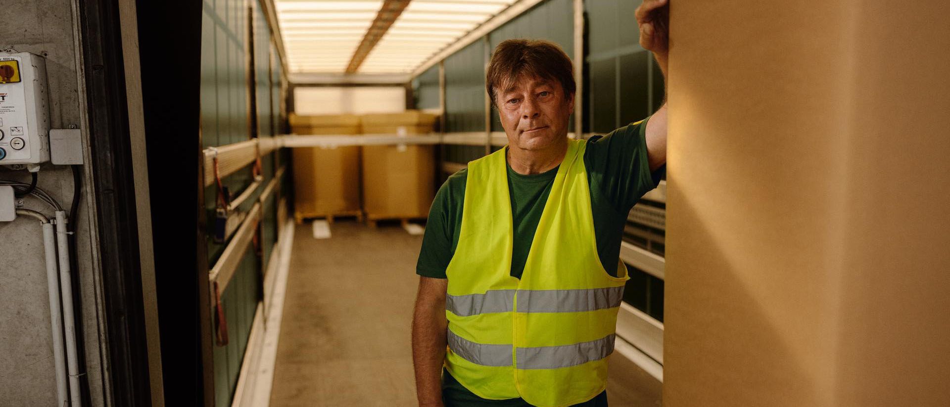 Swiss Post Cargo employee stands leaning against a lorry loading area.