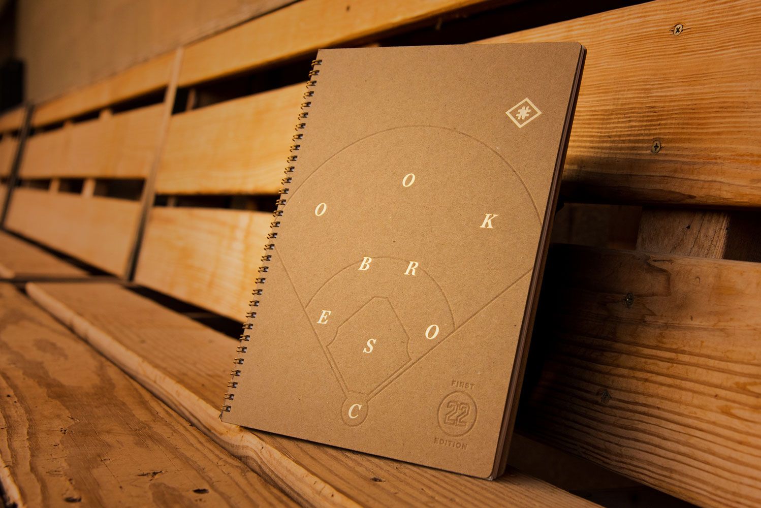 Baseball scorebook resting on a wooden dugout bench at dawn.