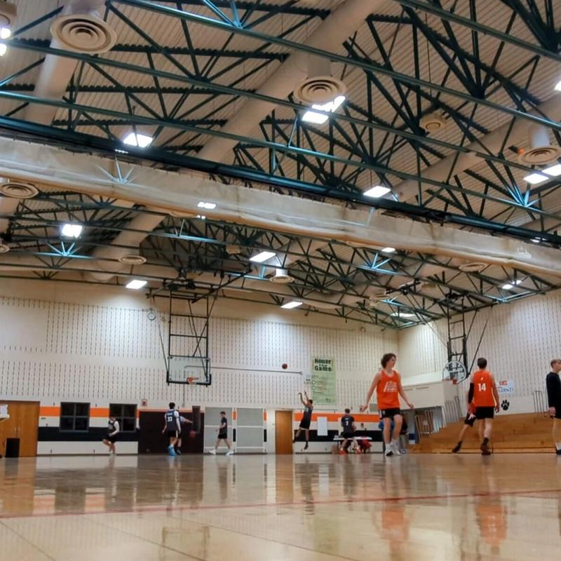 Group of high schoolers playing organized basketball in a gymnasium.