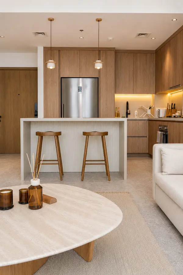 Warm minimalist kitchen and living room in Dubai Hills with oak joinery, stone pendant lights and a travertine countertop