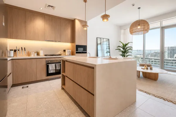 Open-plan kitchen interior design in Dubai with a travertine waterfall island, floor-to-ceiling oak cabinetry. 