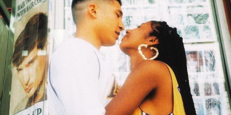 a couple kissing in front of a sign that says open