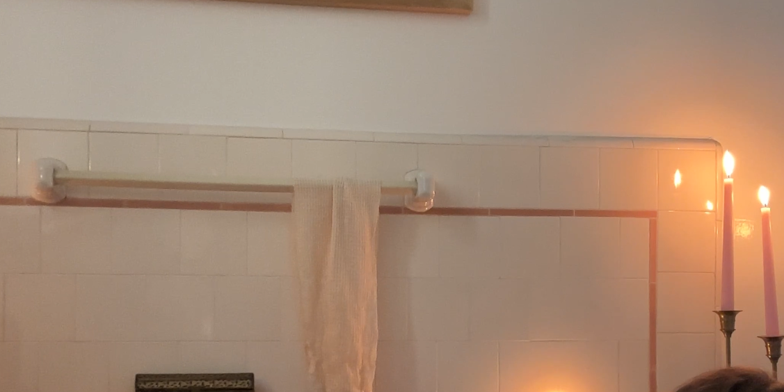 a woman in a bathtub with candles and a picture on the wall above her