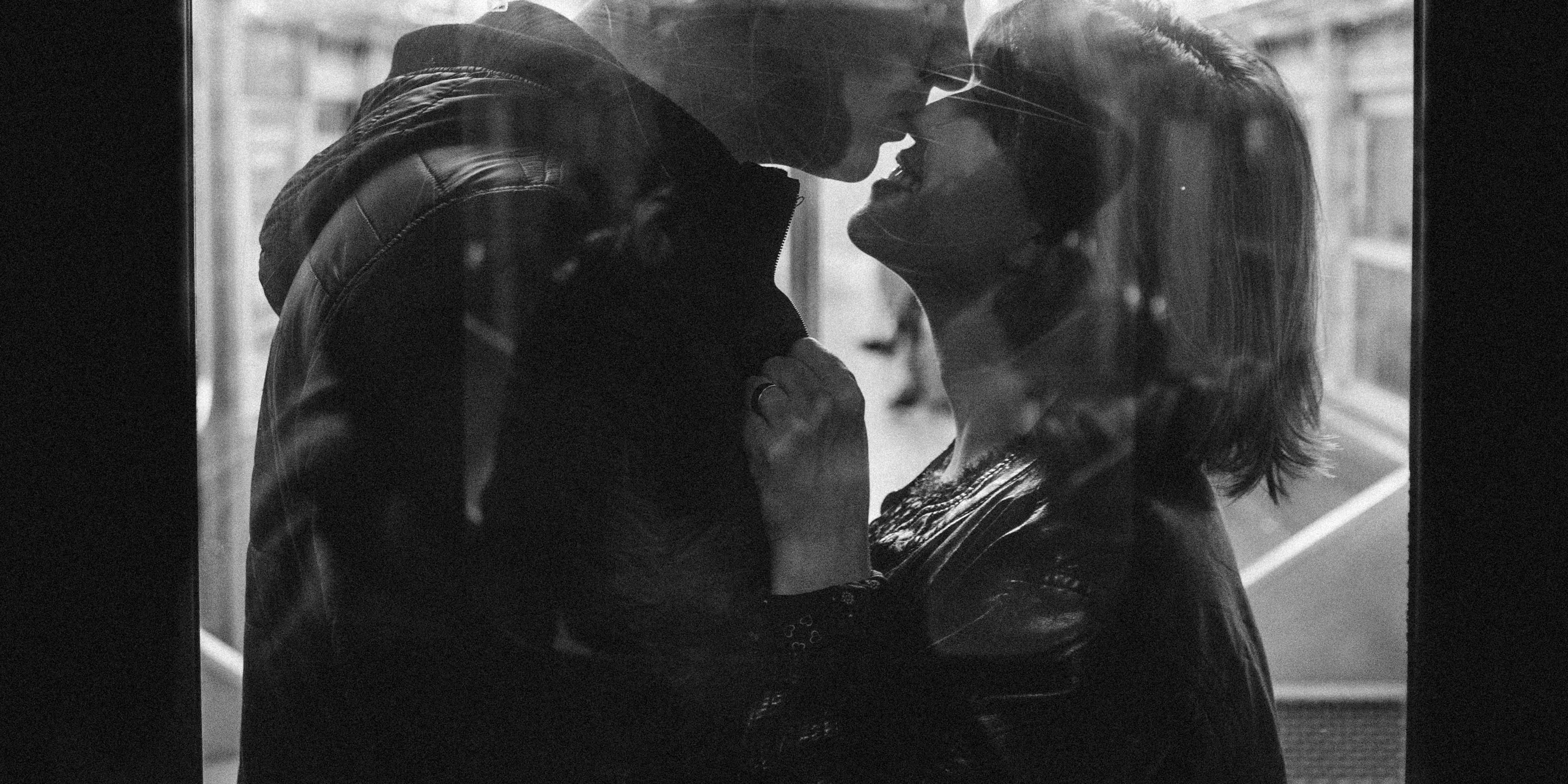 a black and white photo of a man and woman kissing on a train